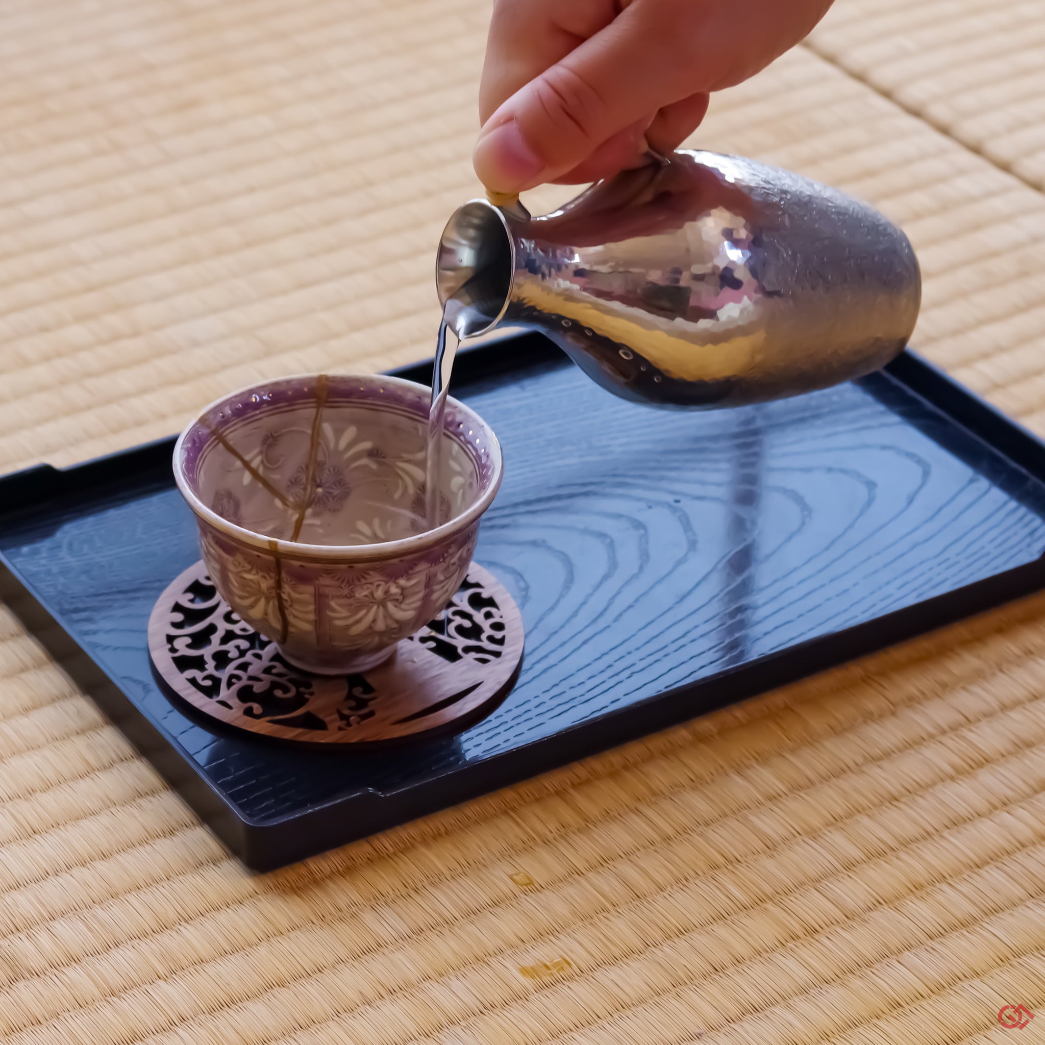 Photo of an authentic Kintsugi pottery piece being used in a real-world setting, such as a cup of sake being poured into a Kintsugi cup