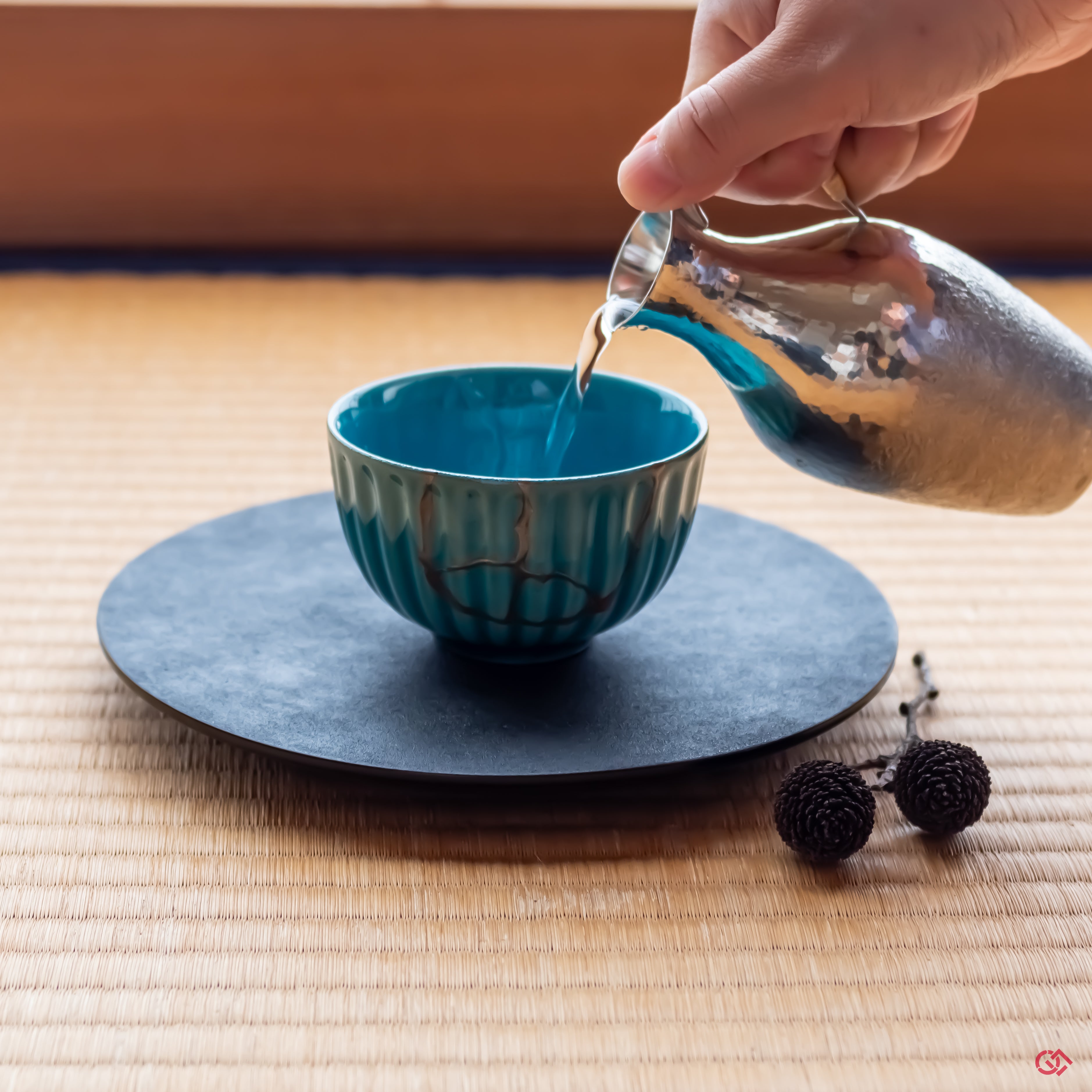 A Kintsugi-restored Arita ware bowl presented in a serene Japanese tearoom. It rests on a black lacquer plate on a traditional tatami mat, with soft light from a shoji screen in the background, creating a scene of wabi-sabi elegance.