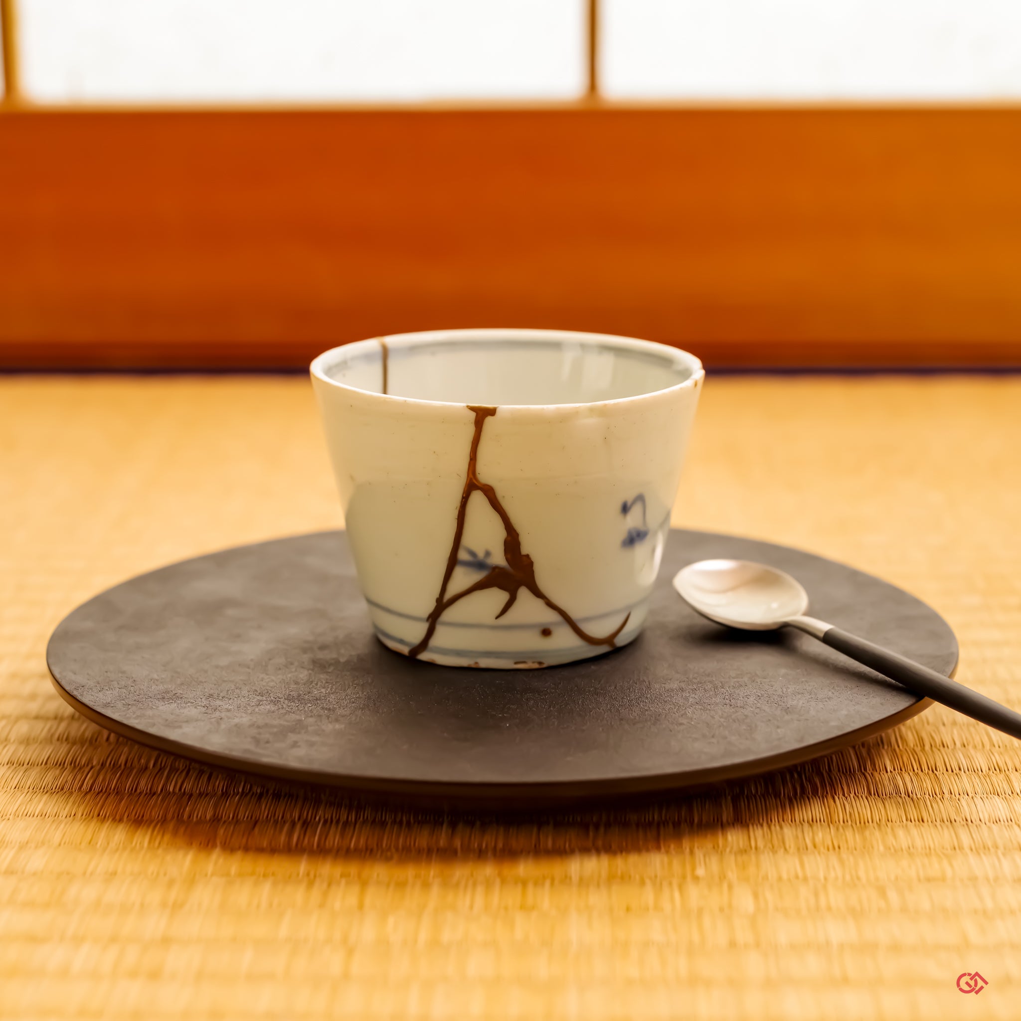 A Kintsugi teacup, restored by a university-trained lacquer artist, resting in a tranquil setting on a traditional tatami mat. The scene captures a harmony between deep-rooted Japanese tradition and a refined, contemporary artistic sensibility.