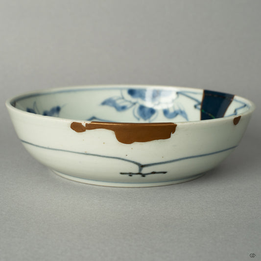 A detailed close-up capturing the soft luster of a 24k gold line against the deep, smooth glaze of the Ko-Imari bowl, honoring its rebirth.