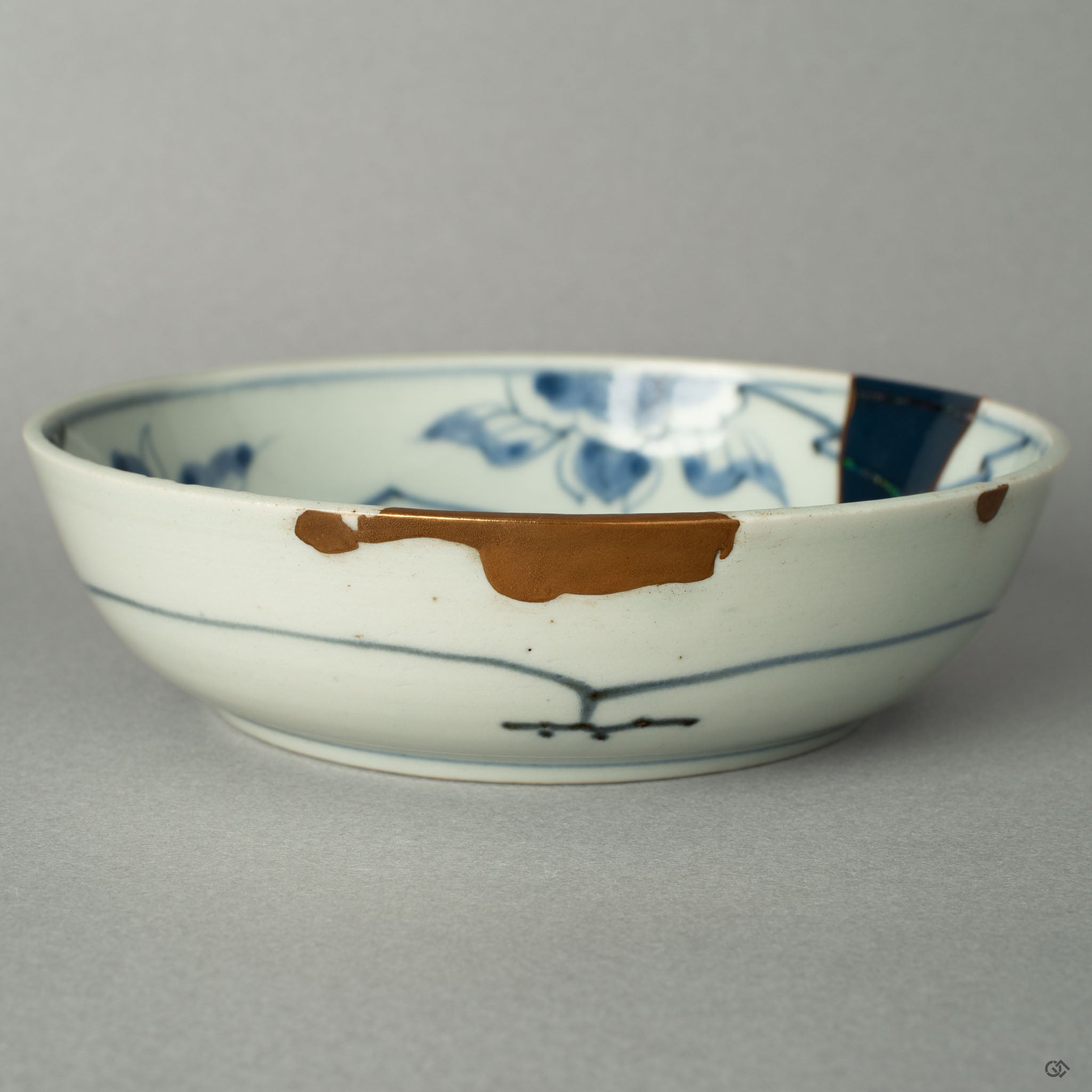 A detailed close-up capturing the soft luster of a 24k gold line against the deep, smooth glaze of the Ko-Imari bowl, honoring its rebirth.