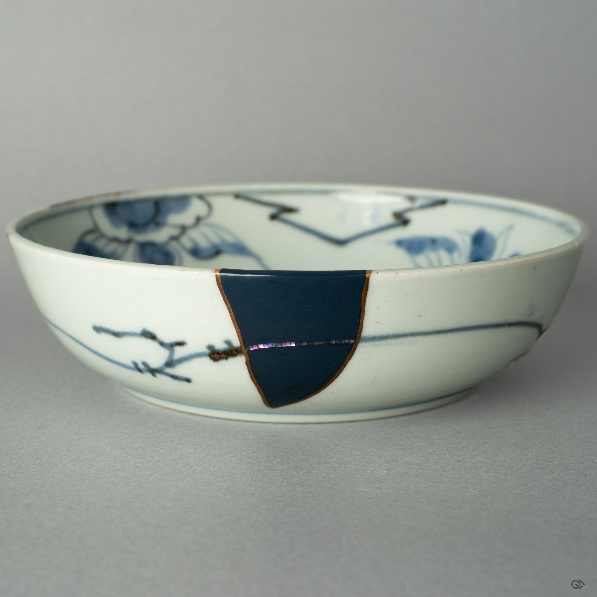 A close-up on the precise point where a 24k gold Kintsugi seam meets the iridescent shimmer of a Raden mother-of-pearl inlay.