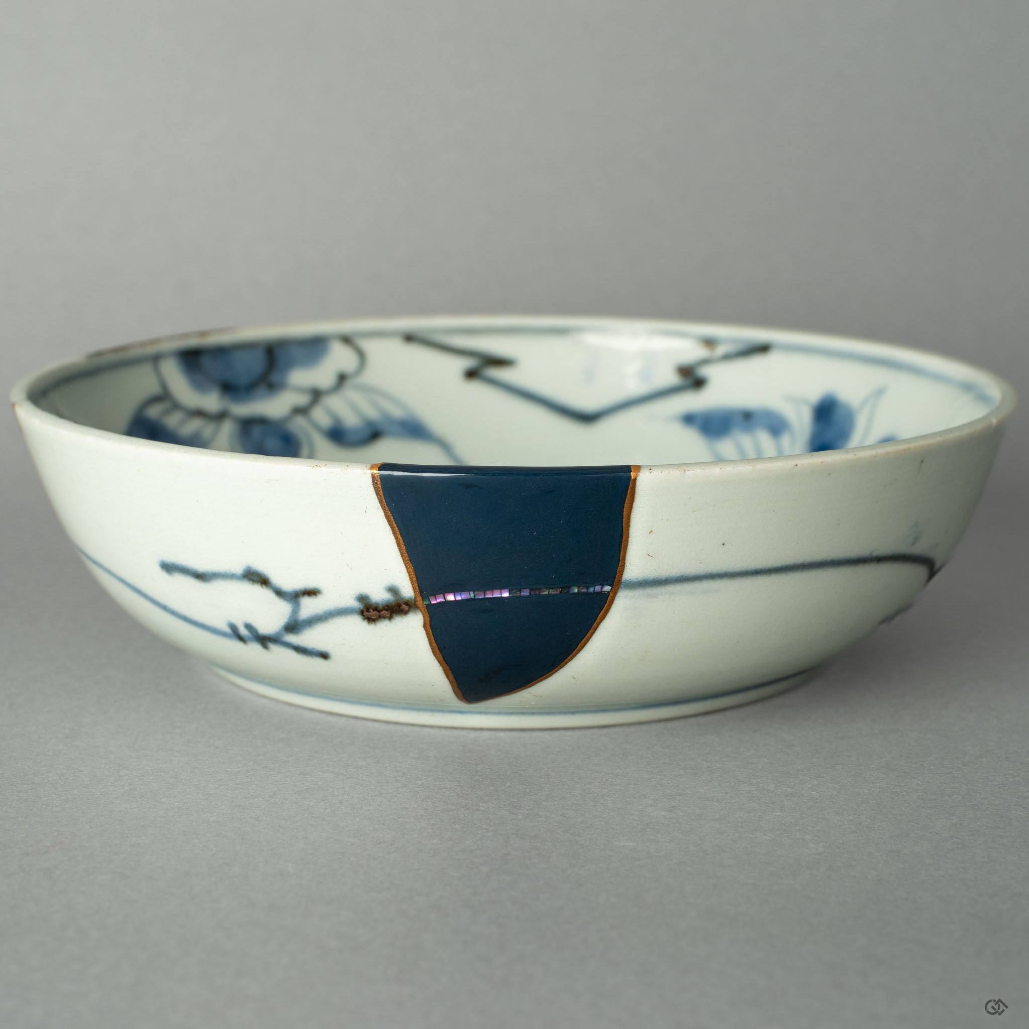 A close-up on the precise point where a 24k gold Kintsugi seam meets the iridescent shimmer of a Raden mother-of-pearl inlay.