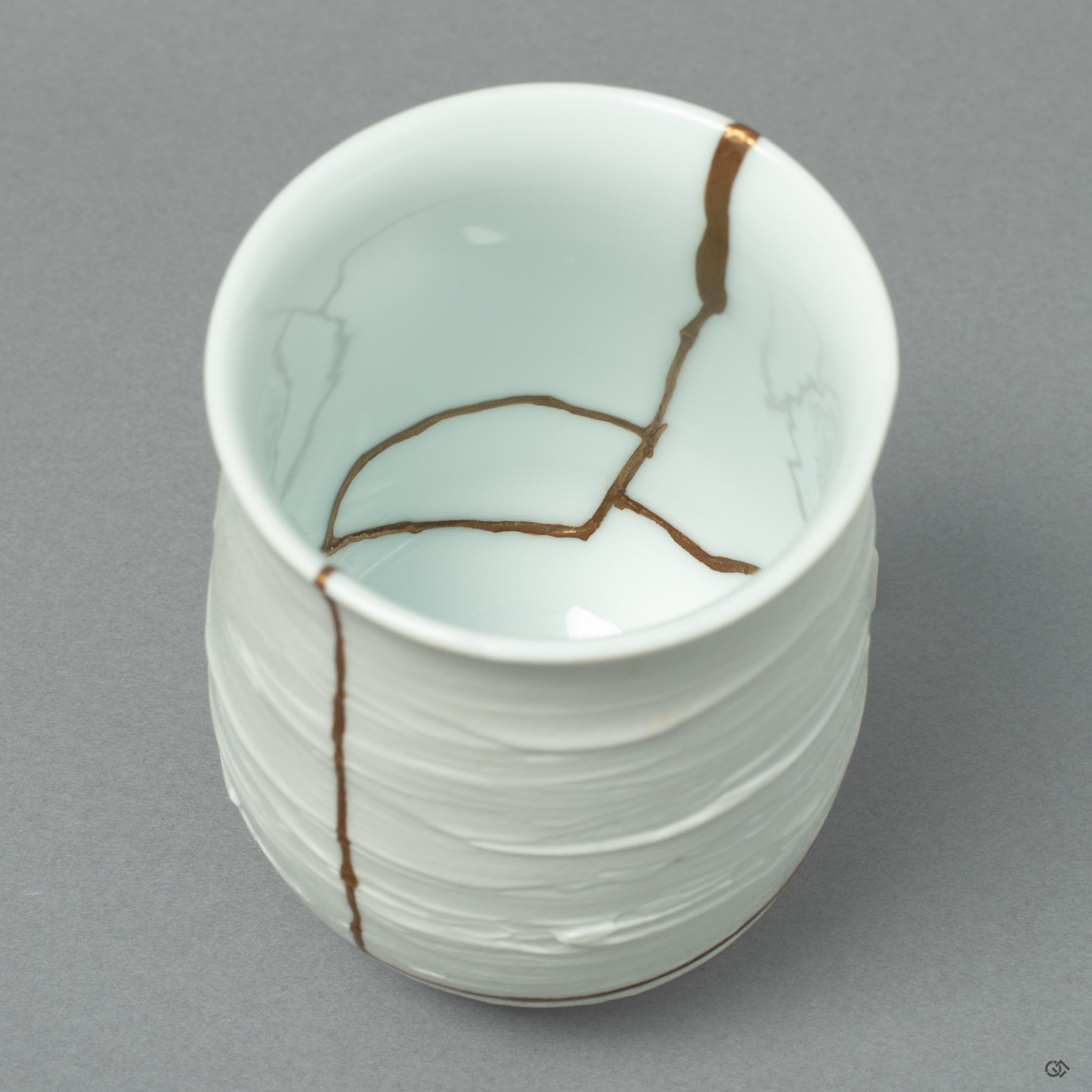 A macro view tracing the path of a 24k gold Kintsugi seam, its soft luster flowing across the pristine white landscape of the Nabeshima porcelain.