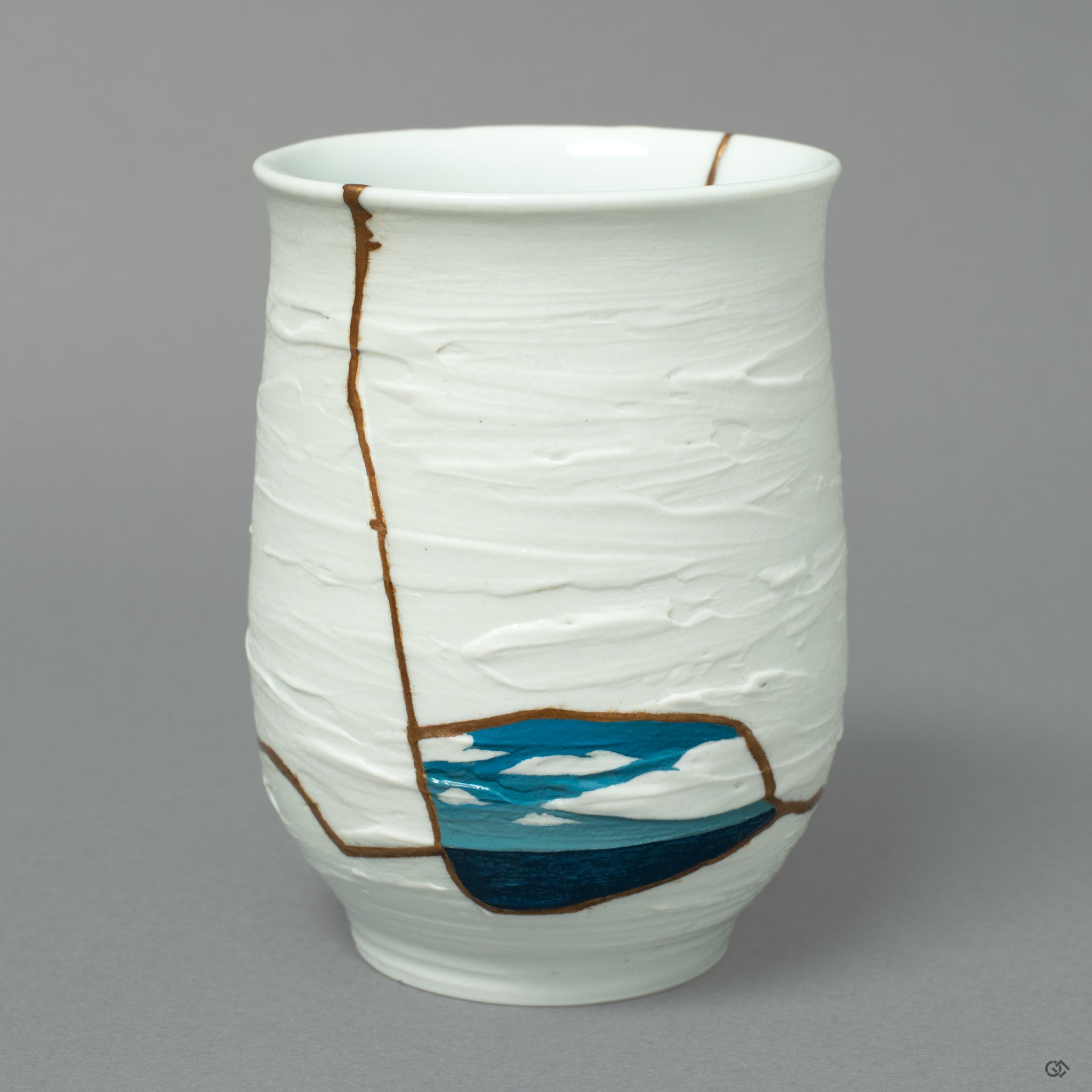 A Nabeshima ware cup, where 24k gold Kintsugi meets a blue Urushi-e painting of the sea and sky, a horizon of art on white porcelain.