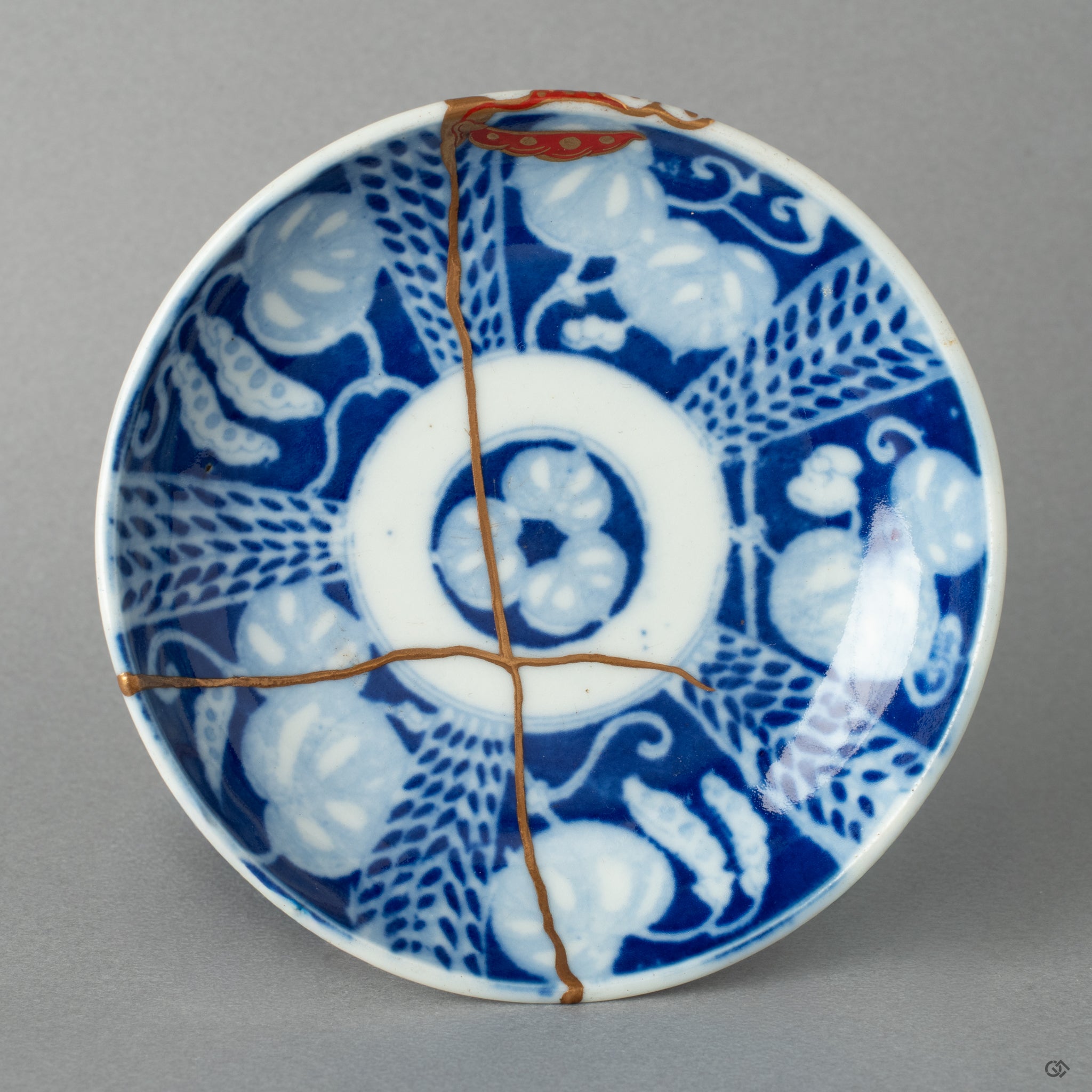 Top-down view of an authentic kintsugi small dish, its golden seams tracing a quiet beauty and from broken to beautiful transformation.