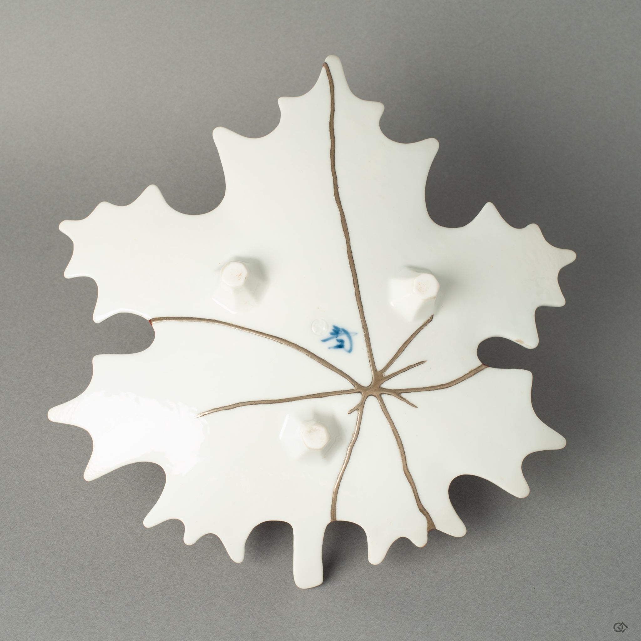 The reverse side of the Arita ware maple leaf dish, revealing a delicate network of pure silver Kintsugi lines. This hidden beauty offers a striking contrast to the vermillion top, showcasing the multifaceted nature of this unique artwork.