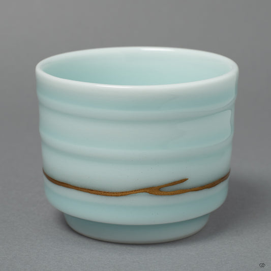 The serene form of an Arita ware sake cup, its story honored by fine seams of 24k gold Kintsugi that trace a path of quiet beauty.