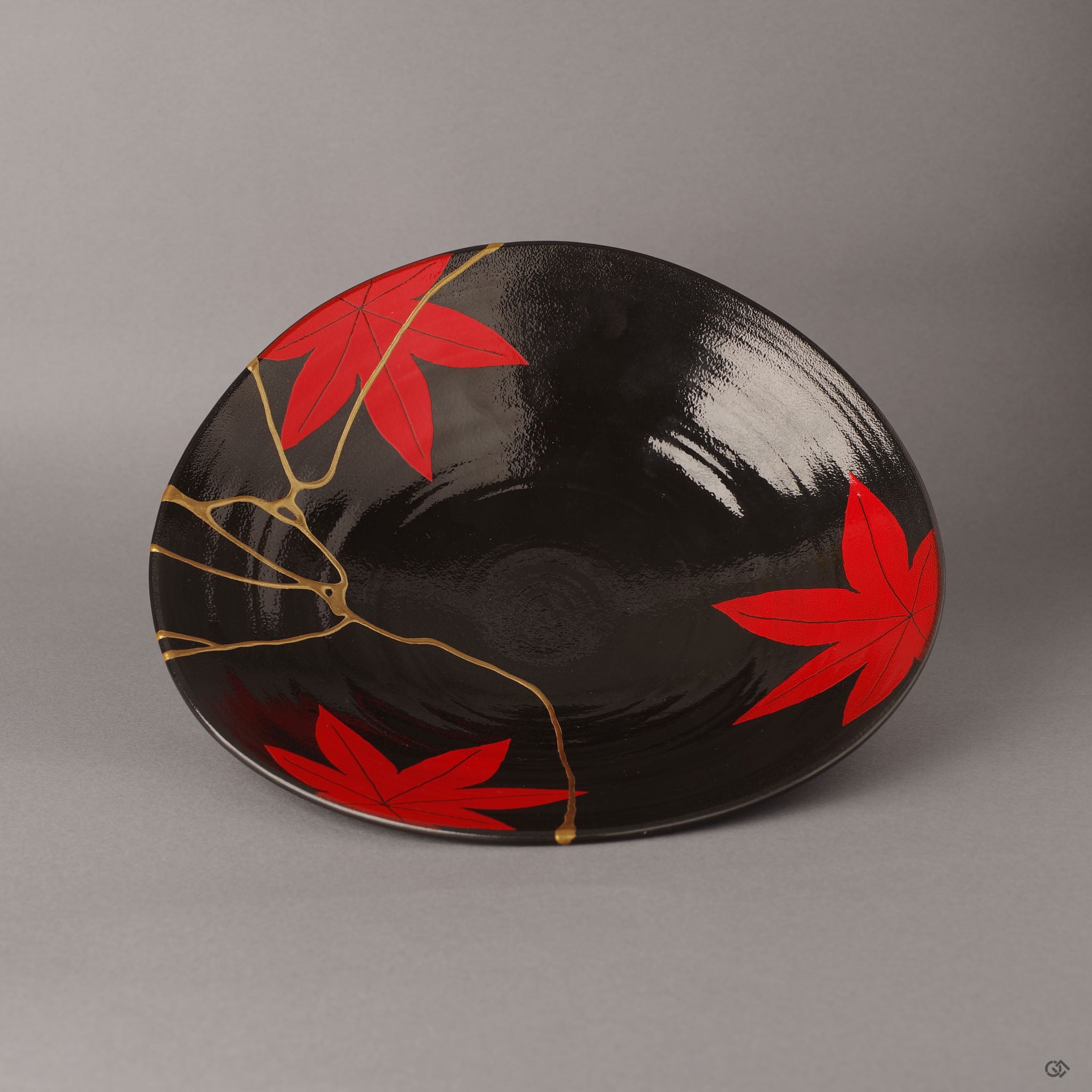 Front view of an Arita ware kintsugi bowl, its shallow open form inviting vulnerability and release—24K gold seams tracing strength across the dramatic black and crimson maple design.