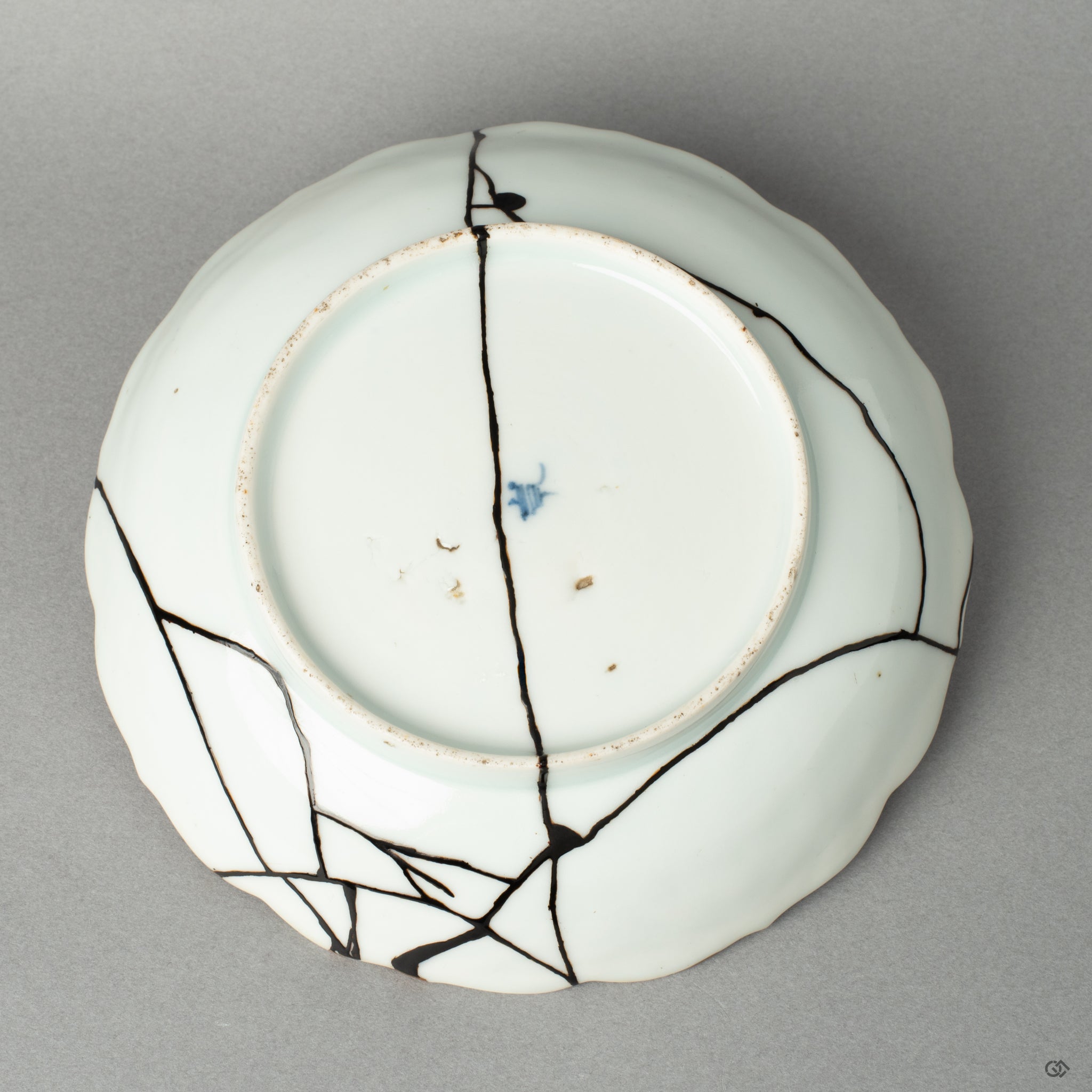The antique base of a Ko-Imari bowl, its makers mark preserved alongside the subtle kintsugi mend, an act of honoring history.