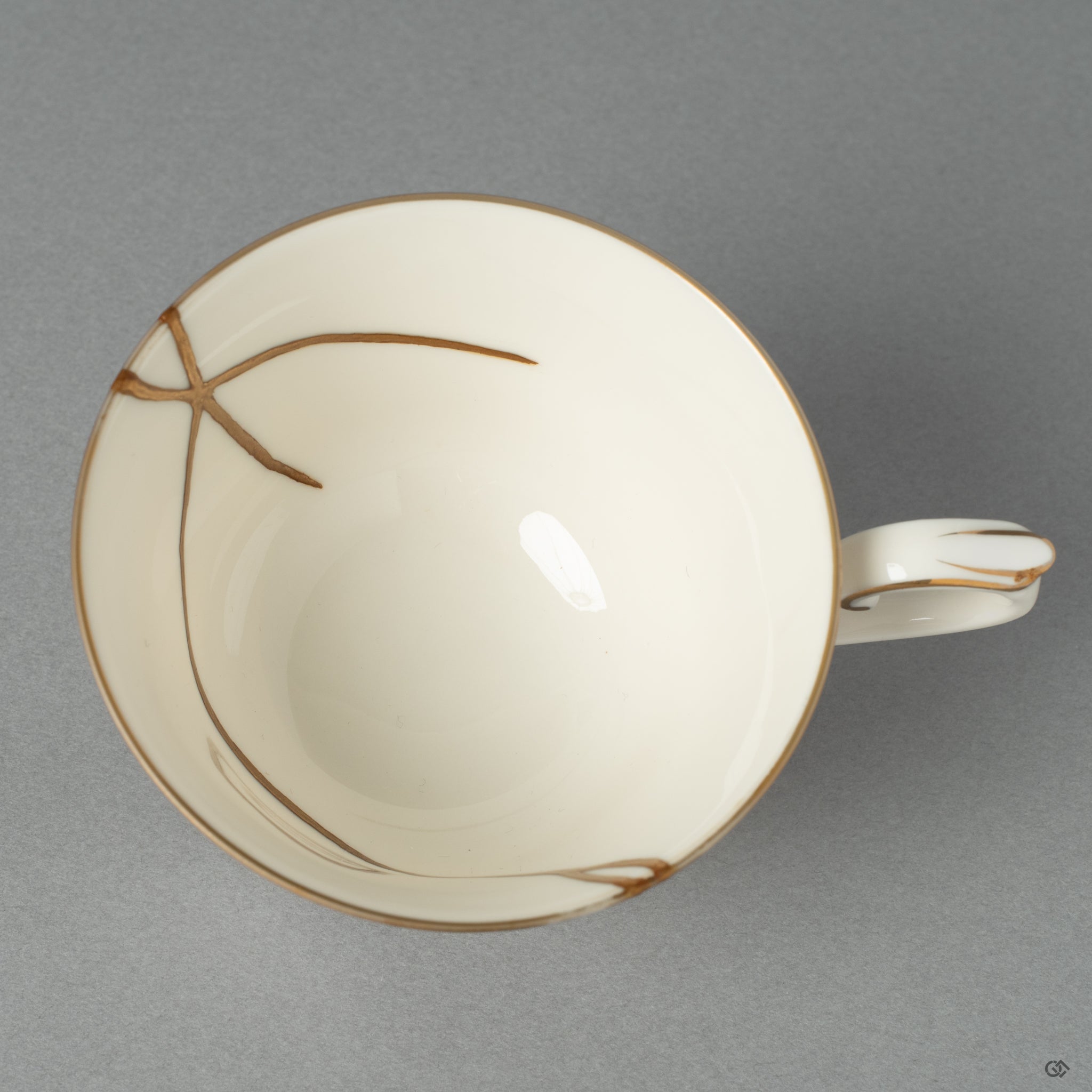 A top-down view of an authentic Japanese Kintsugi Cup & Saucer repaired with 24K Gold artistry, revealing the harmony between the original form and its golden seams.
