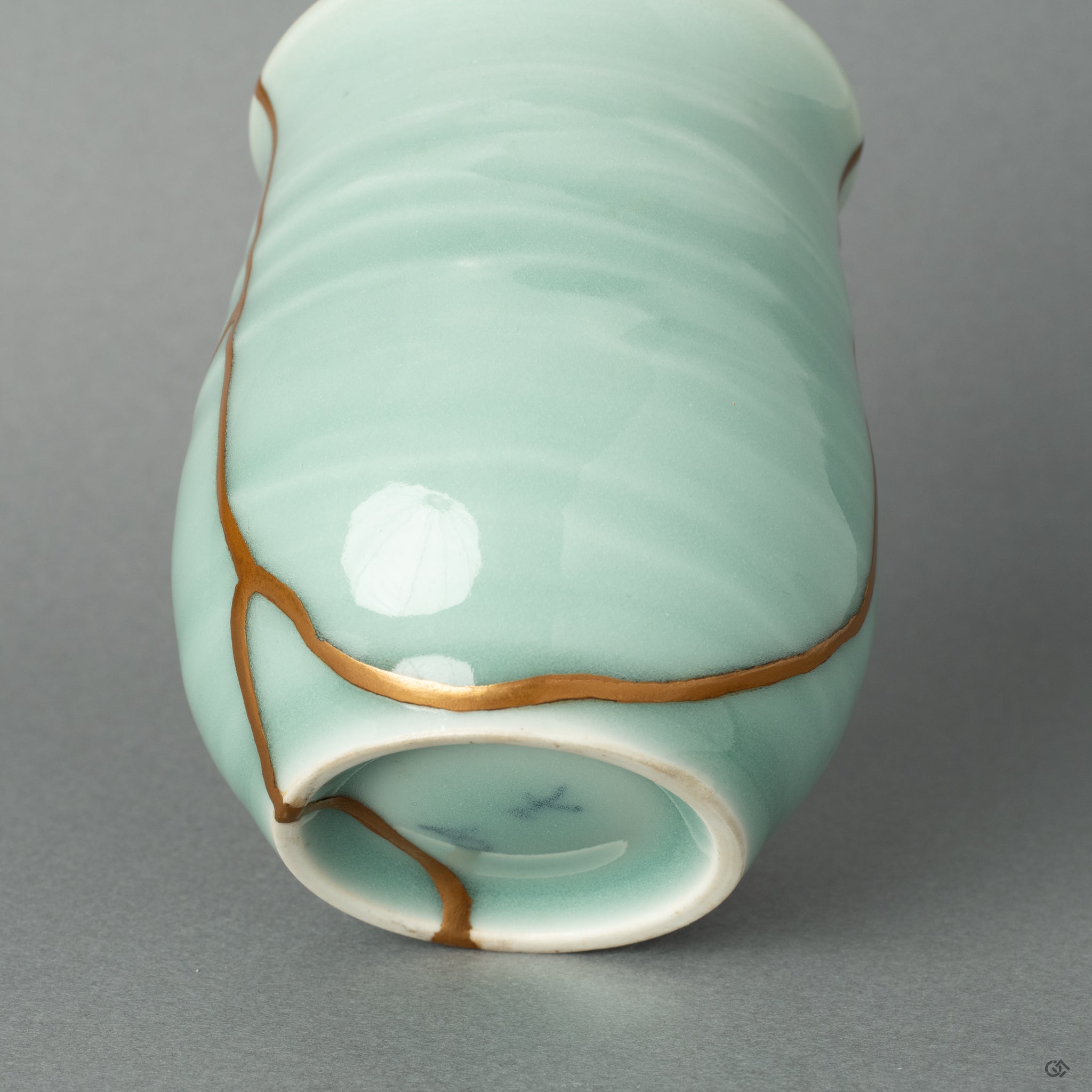 This close-up reveals the seamless transition from the cool celadon ceramic to the warm gold, a quiet luxury that speaks to the art of imperfection.