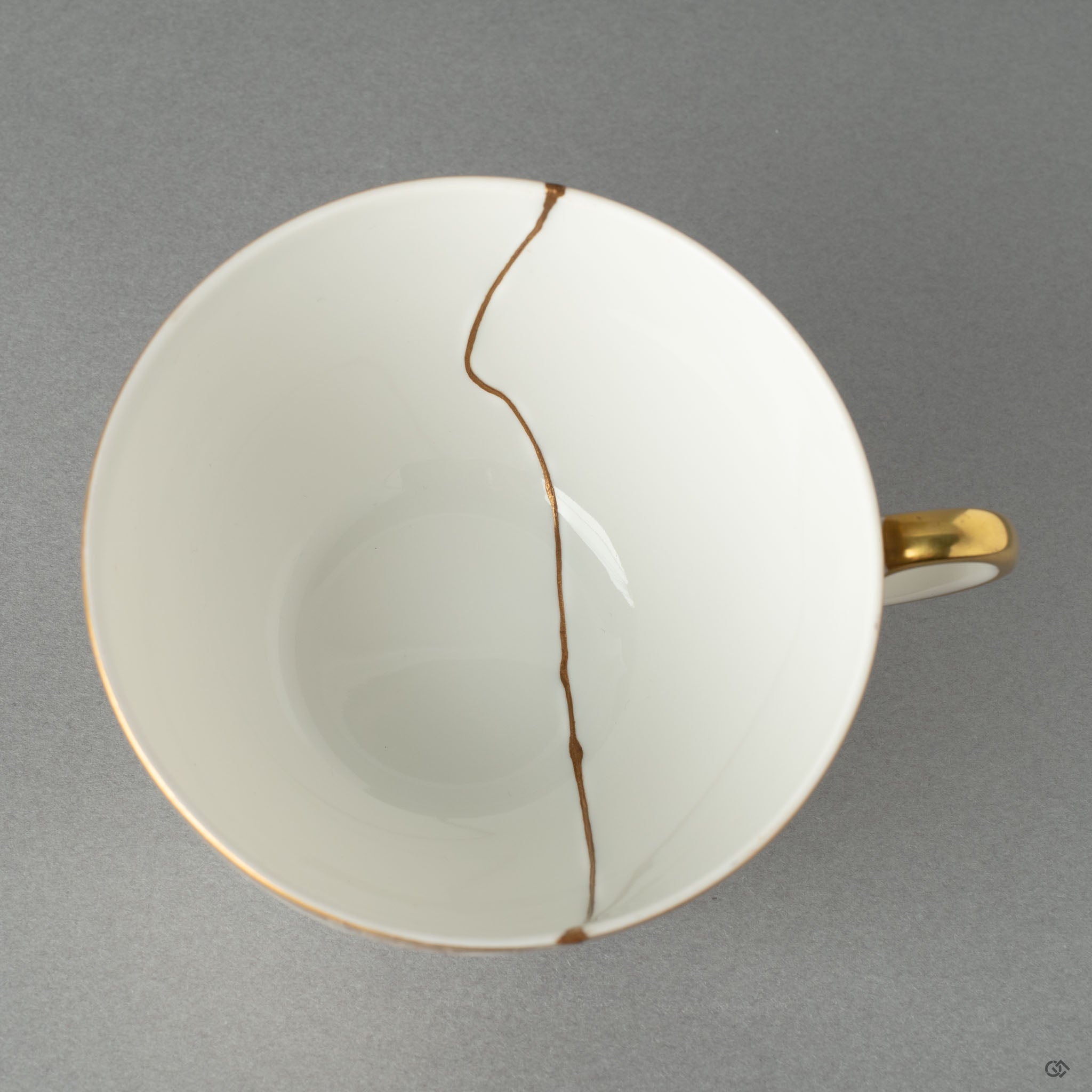 Top-down view of a kintsugi tea cup, its golden joinery tracing a quiet beauty that speaks of rebirth and renewal.