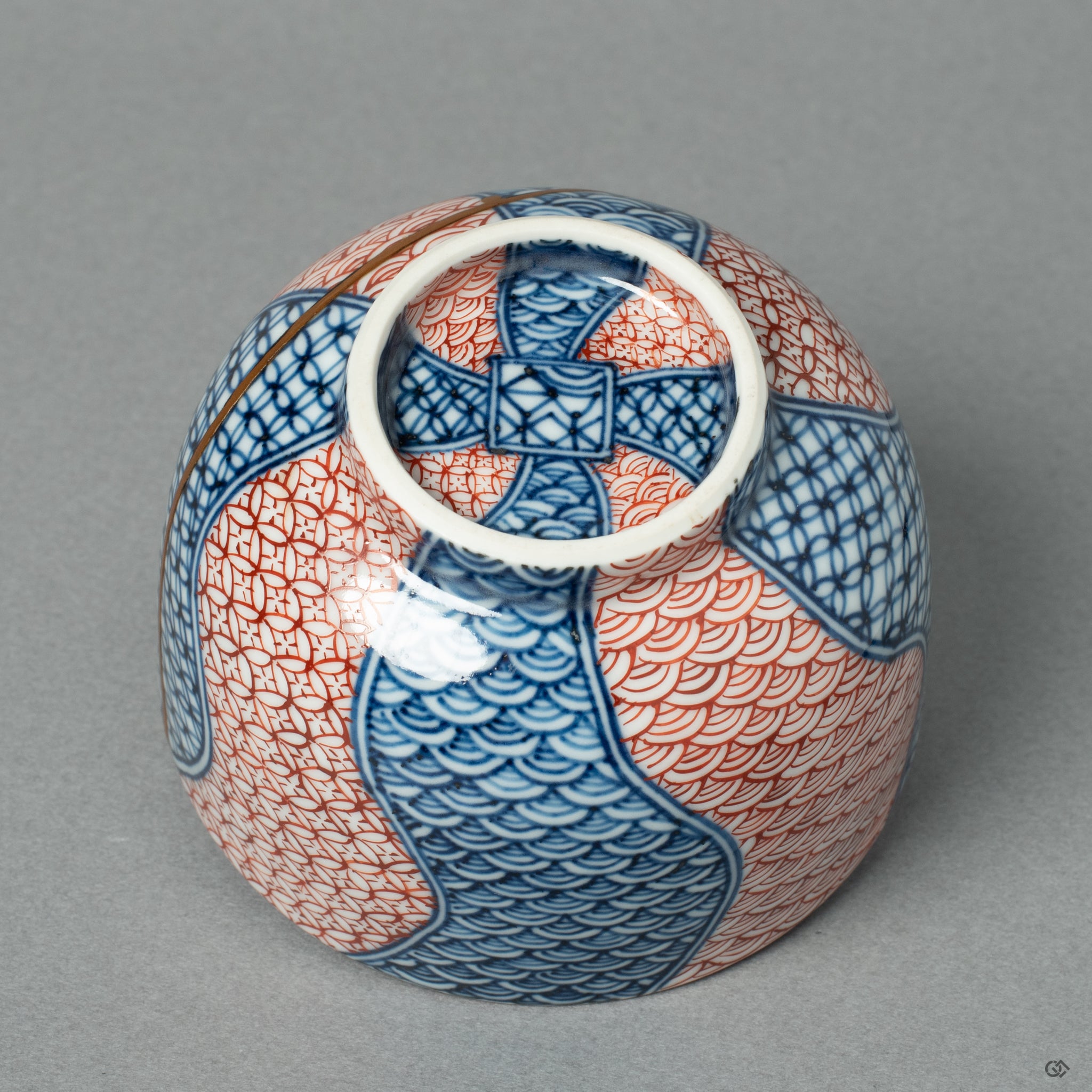 View of the footed base of a Kyoto ware tea cup, showing the continuation of the 24k gold Kintsugi repair on the underside of the piece.