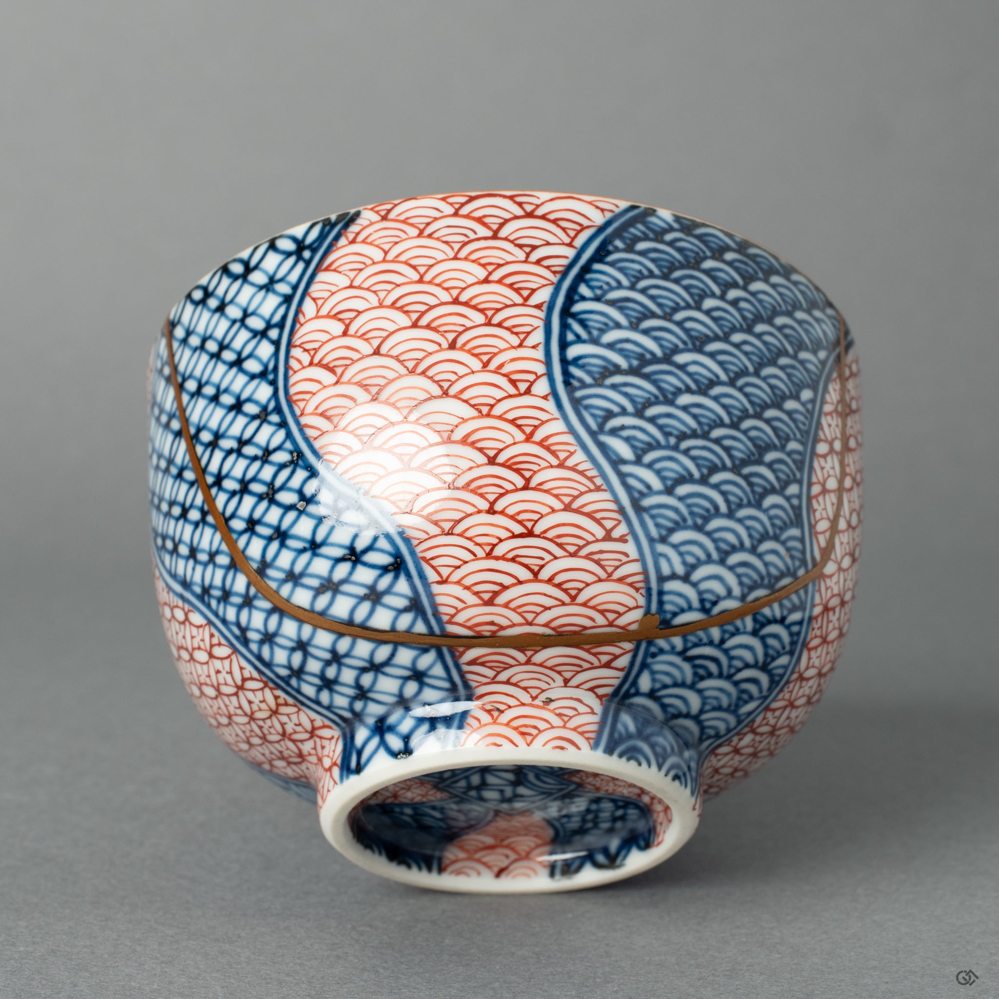 A detailed close-up of a Kyoto ware tea cup, highlighting the texture and luster of the 24k gold Kintsugi seam against the ceramic glaze.