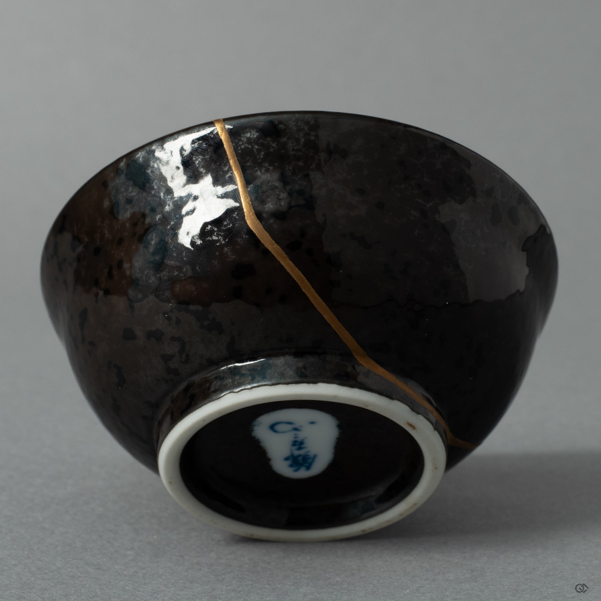 The shining 24K gold kintsugi seam on the ceramic surface, a quiet moment where the vessels journey becomes history made visible.