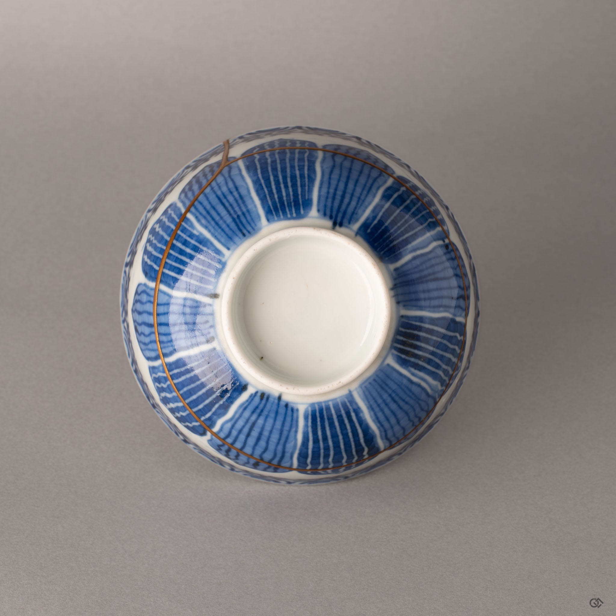 Bottom view of kintsugi Ko-Imari bowl showing foot ring and porcelain base with gold seam visible, Japanese craftsmanship from below.
