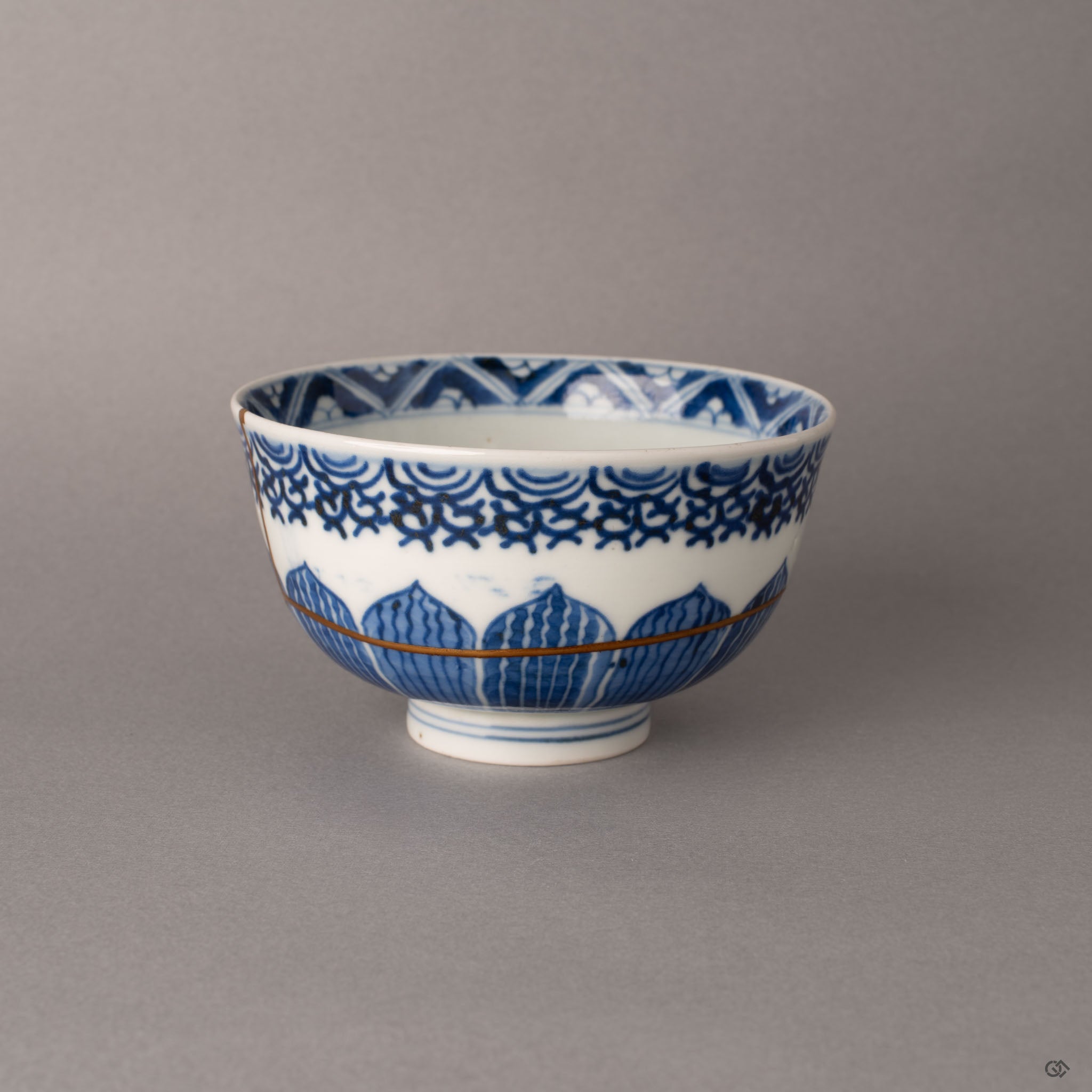 Side view of kintsugi Ko-Imari bowl showing gold restoration line from rim to body across cobalt blue patterns, history made visible.