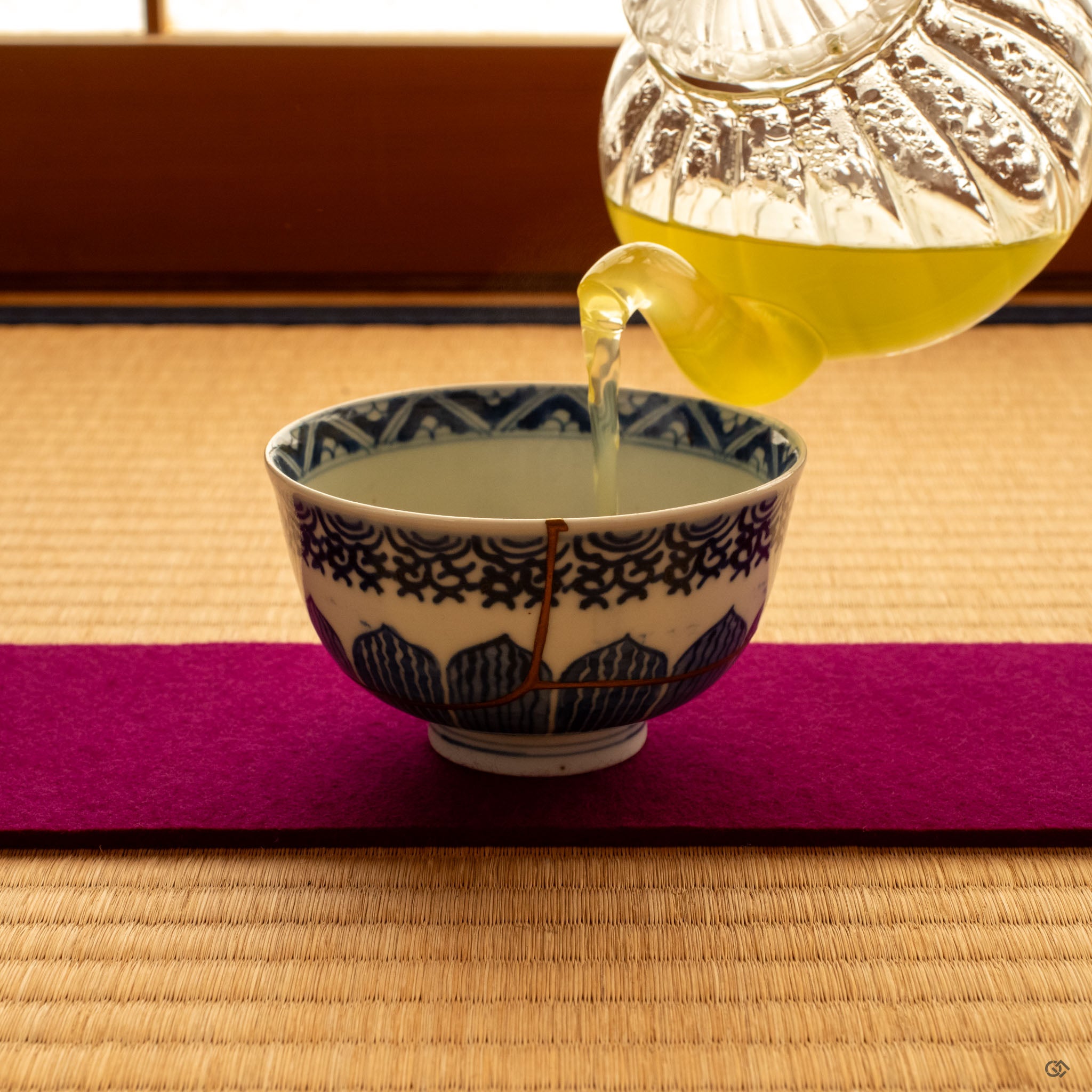 Kintsugi Ko-Imari bowl on tatami mat in warm natural light, sometsuke blue and gold seams creating a moment of contemplation.