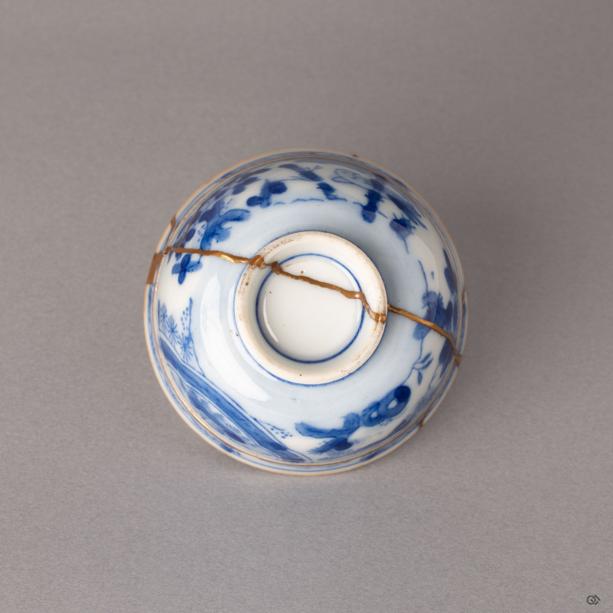 Bottom of kintsugi Ko-Imari cup showing foot ring and gold restoration extending to the base, enduring legacy in porcelain and gold.
