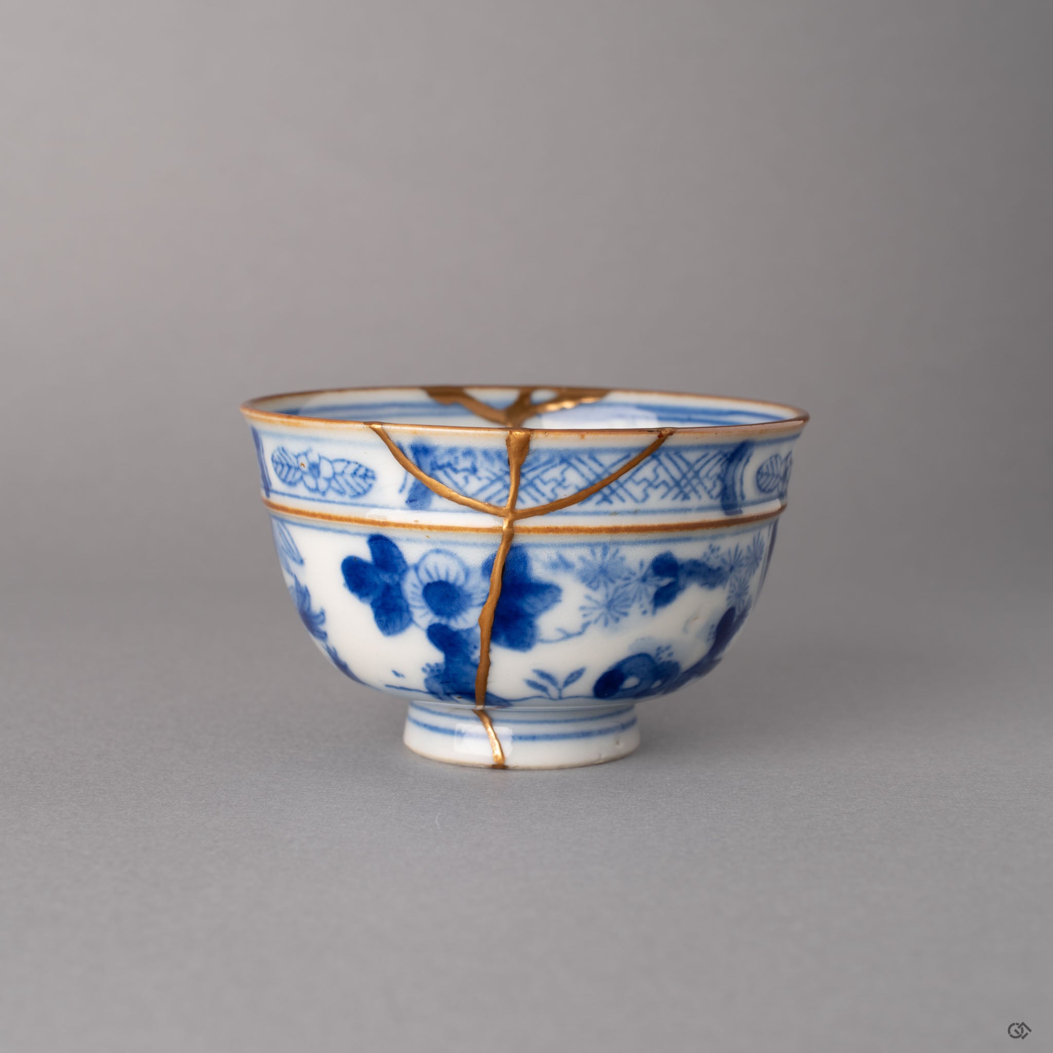 Side view of kintsugi Ko-Imari cup showing gold restoration lines through cobalt blue panels, antique porcelain with tactile history.