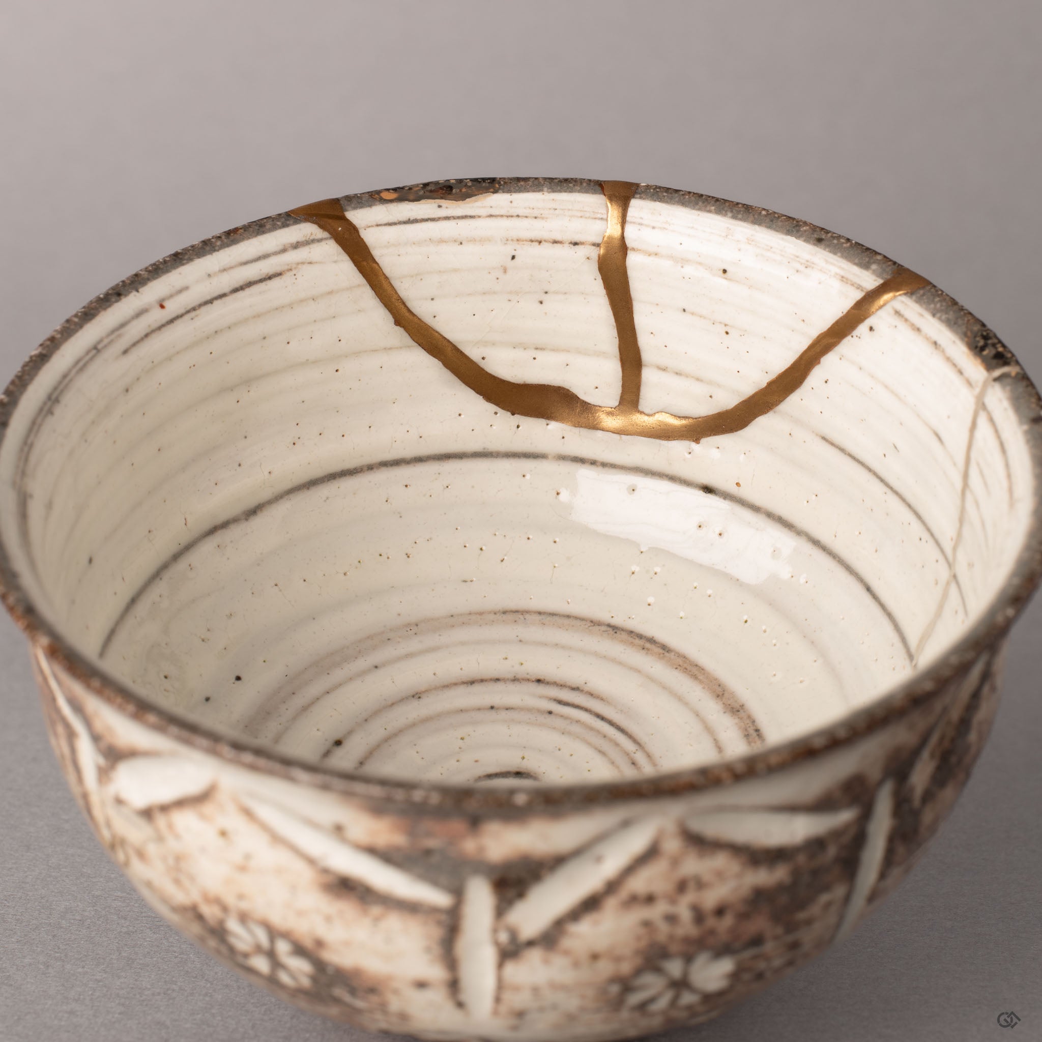Interior of a kintsugi Kyoto cup showing pure silver restoration lines against cream glaze, history made visible in each restored seam.