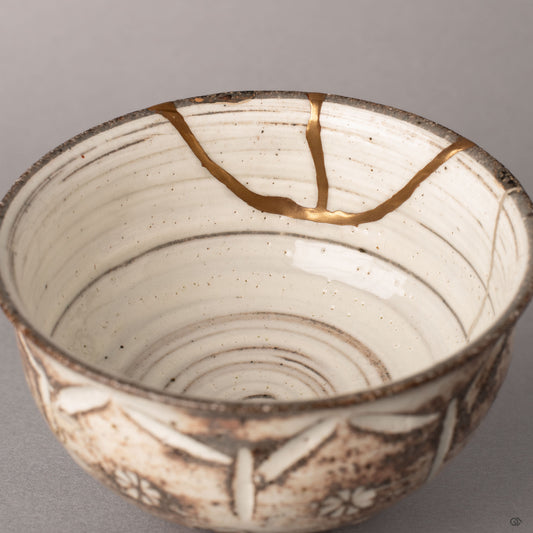 Interior of a kintsugi Kyoto cup showing pure silver restoration lines against cream glaze, history made visible in each restored seam.