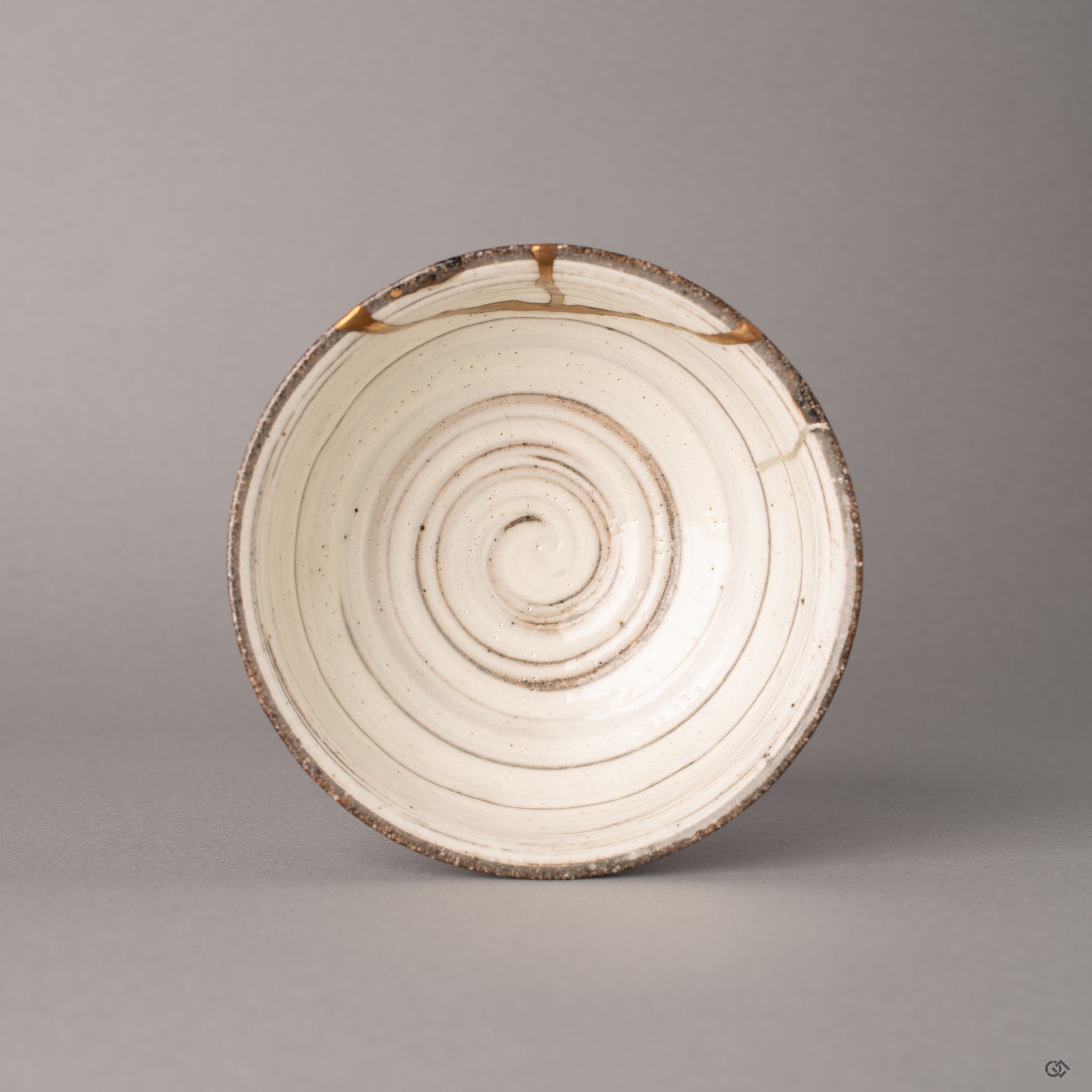 Top view of a kintsugi Kyoto earthenware cup with gold and silver seams crossing the rim, perfectly imperfect in its restored form.