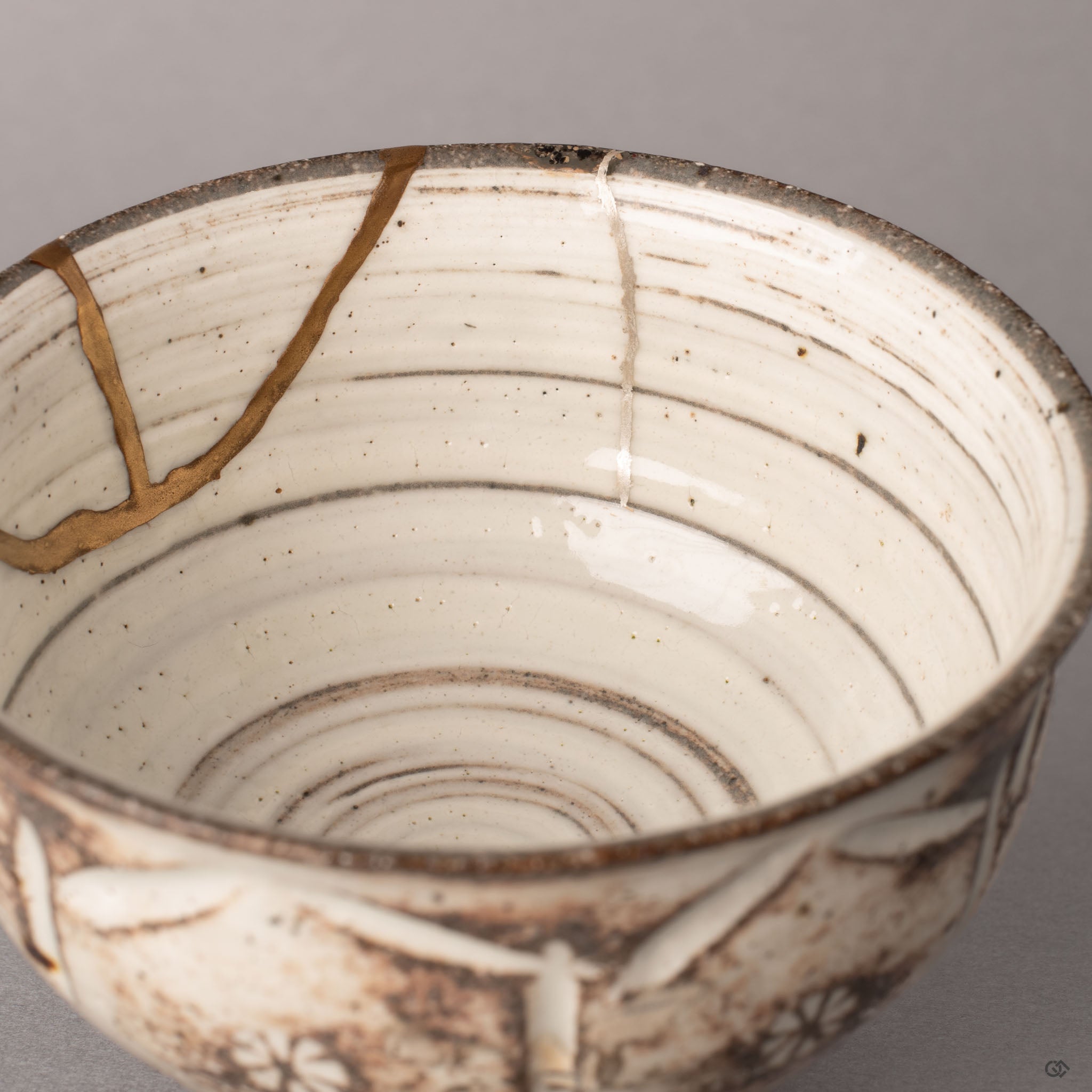 Close-up of pure silver gintsugi restoration inside a Kyoto ware kintsugi cup, the restored fractures carrying an enduring legacy in silver.