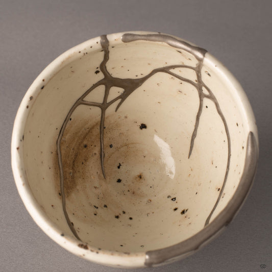 Interior close-up of silver kintsugi lines inside Shigaraki cup, urushi lacquer beneath the silver finish, tactile history.
