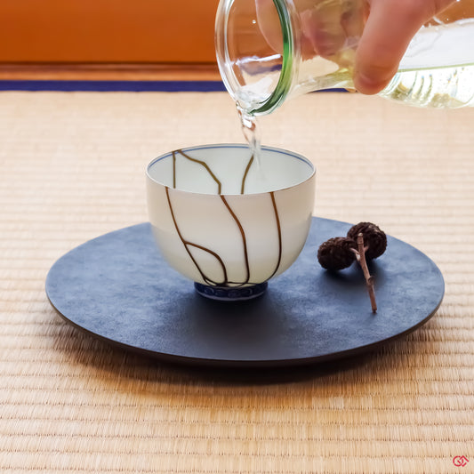 Photo of an authentic Kintsugi pottery piece being used in a real-world setting, such as a cup of sake being poured into a Kintsugi cup