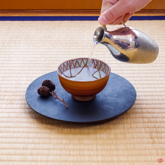 Photo of an authentic Kintsugi pottery piece being used in a real-world setting, such as a cup of sake being poured into a Kintsugi cup