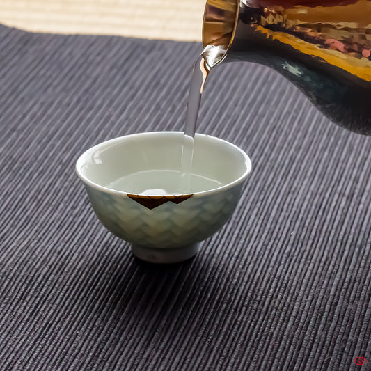 Photo of an authentic Kintsugi pottery piece being used in a real-world setting, such as a cup of sake being poured into a Kintsugi cup