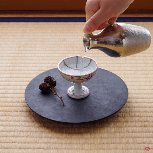 Photo of an authentic Kintsugi pottery piece being used in a real-world setting, such as a cup of sake being poured into a Kintsugi cup