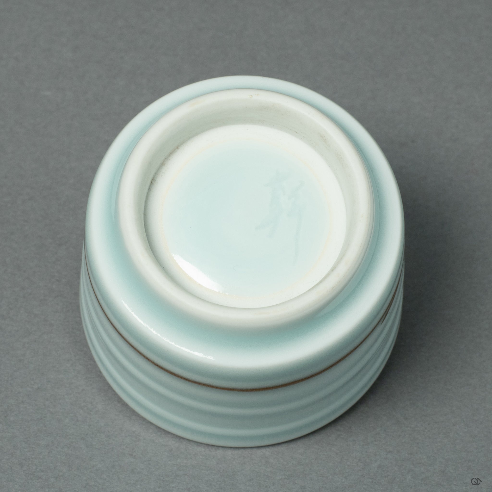 The foot (koudai) of the Arita ware sake cup, revealing the clean porcelain base and the point where the 24k gold Kintsugi repair gracefully terminates.