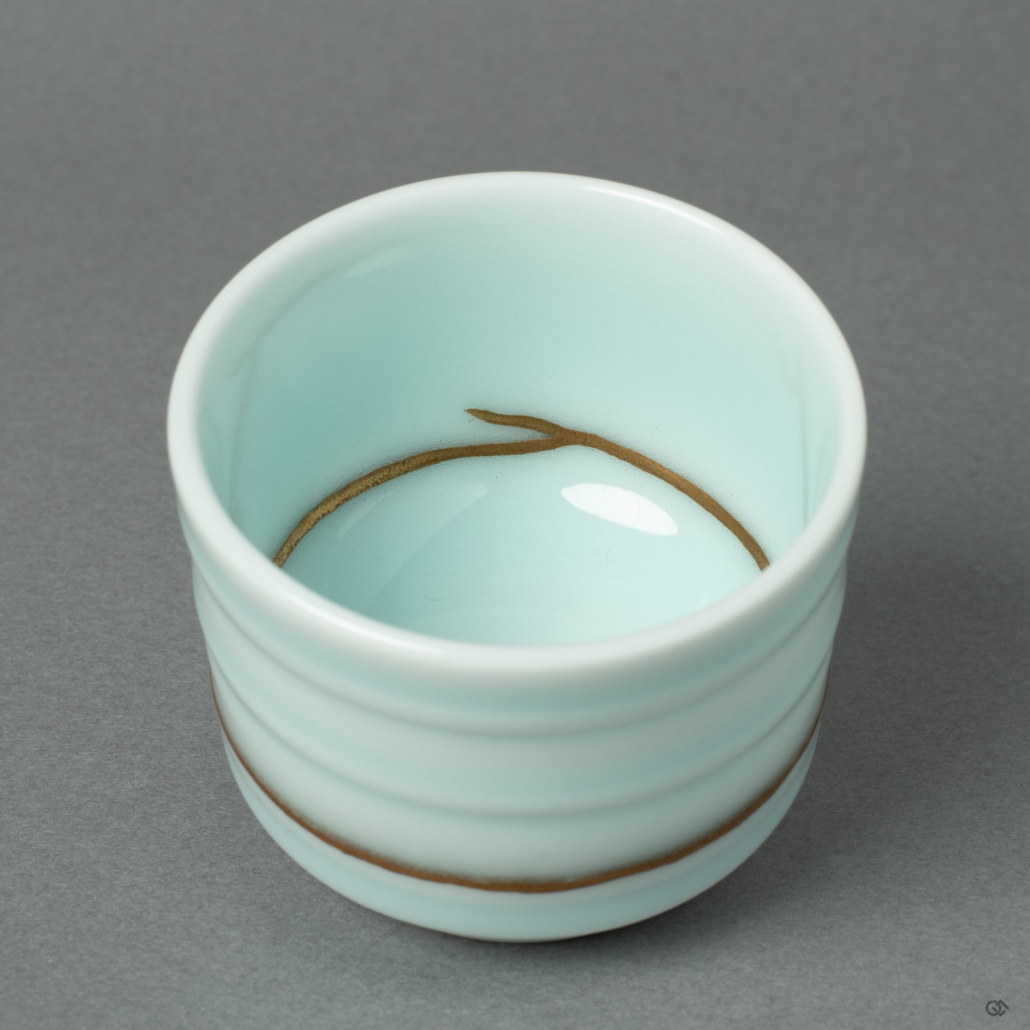 A detailed macro view of a 24k gold Kintsugi seam on the Arita ware porcelain. This close-up reveals the meticulous application of urushi lacquer and rich gold powder.