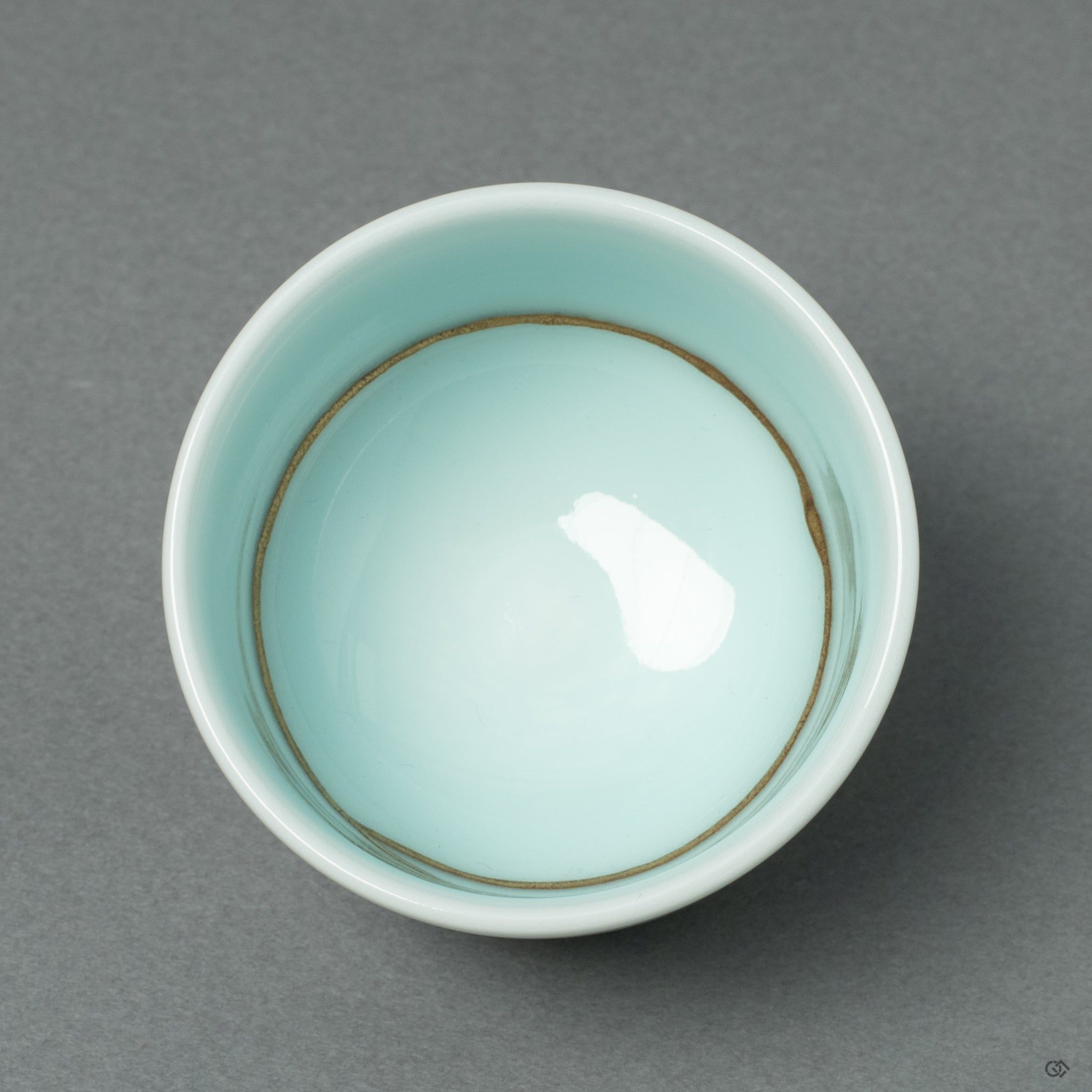 A view into the Kintsugi sake cup from above, showing the golden repair lines continuing into the pristine white interior, creating a beautiful harmony.