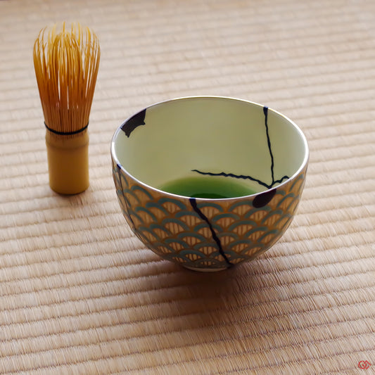 A photo of an authentic Kintsugi pottery piece being used in a real-world setting, such as a tea bowl of green tea being poured into a Kintsugi teabowl.