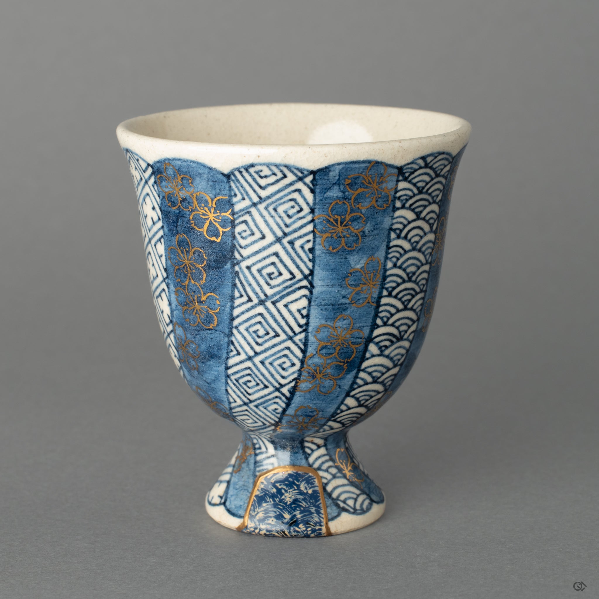A Kyoto ware sake cup, where 24k gold Kintsugi and a textured Kawari-nuri Seigaiha wave pattern exist in quiet harmony.