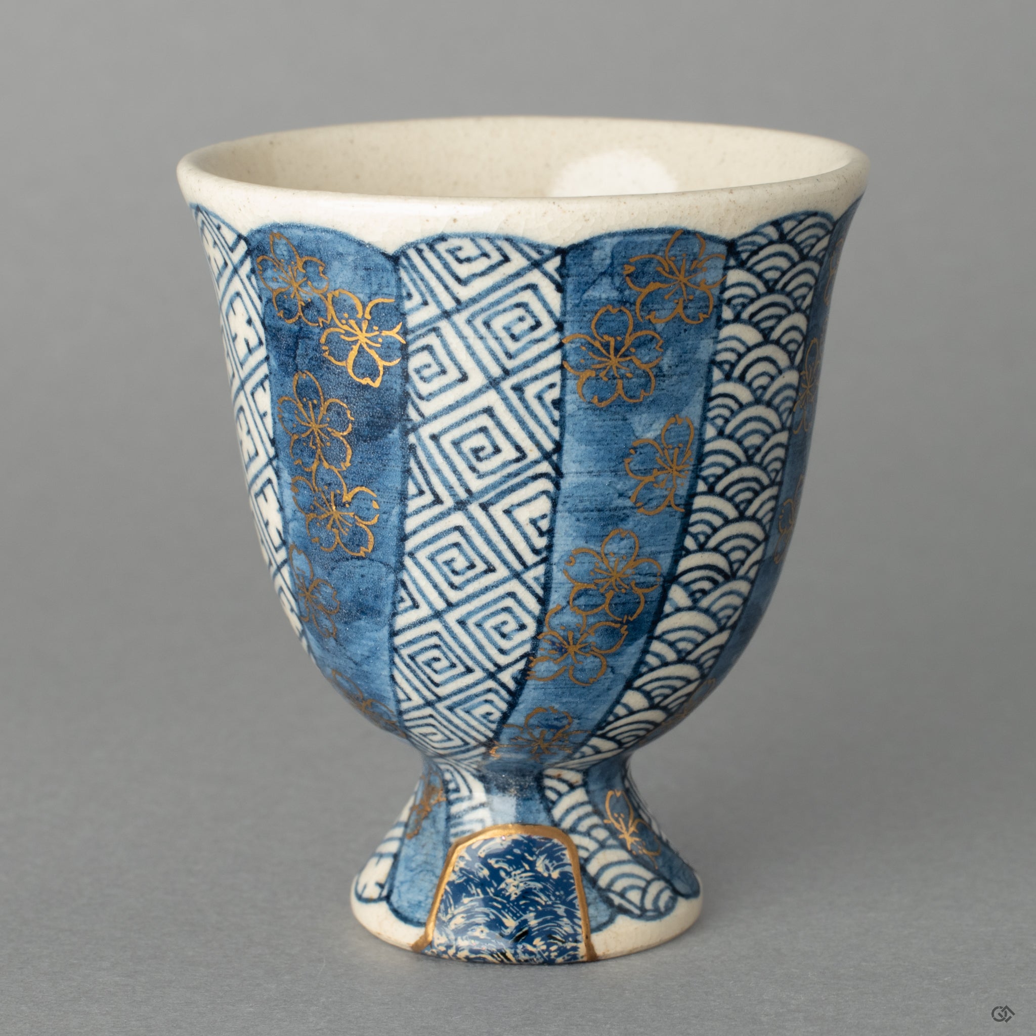 A Kyoto ware sake cup, where 24k gold Kintsugi and a textured Kawari-nuri Seigaiha wave pattern exist in quiet harmony.