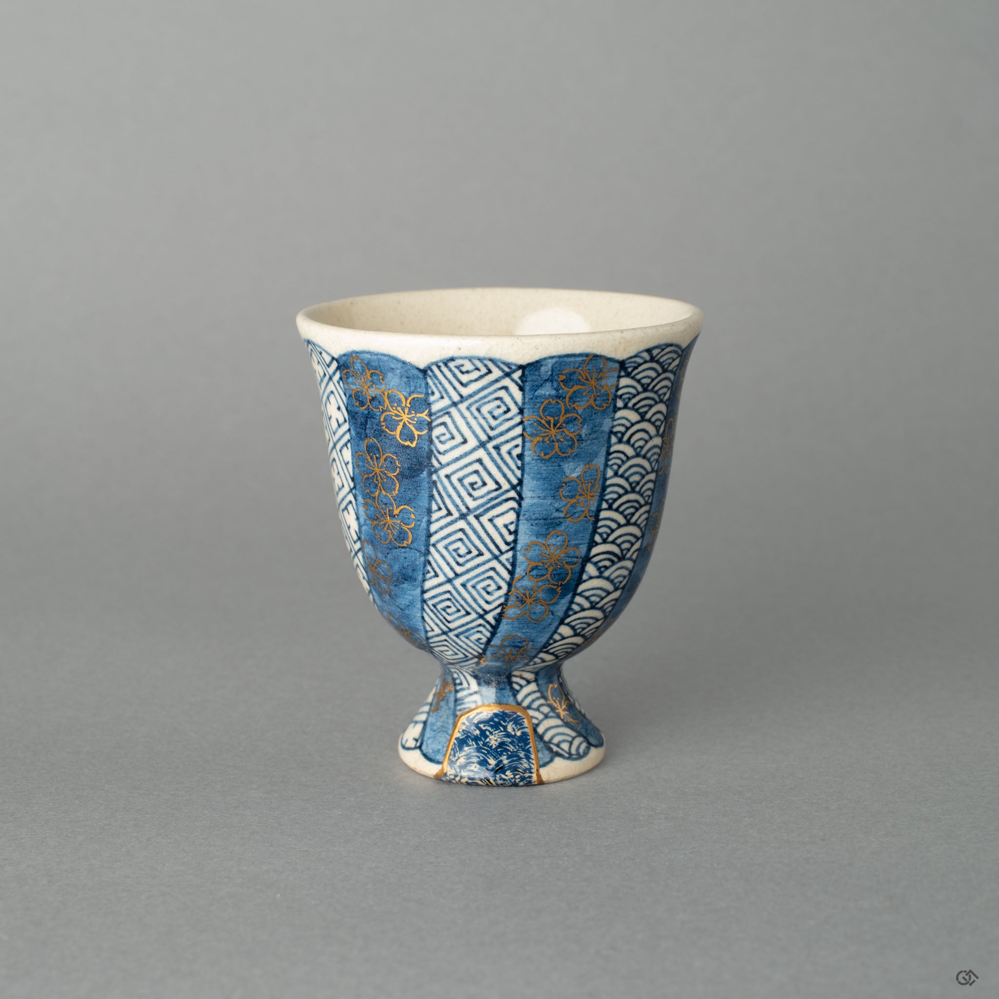 A Kyoto ware sake cup, where 24k gold Kintsugi and a textured Kawari-nuri Seigaiha wave pattern exist in quiet harmony.