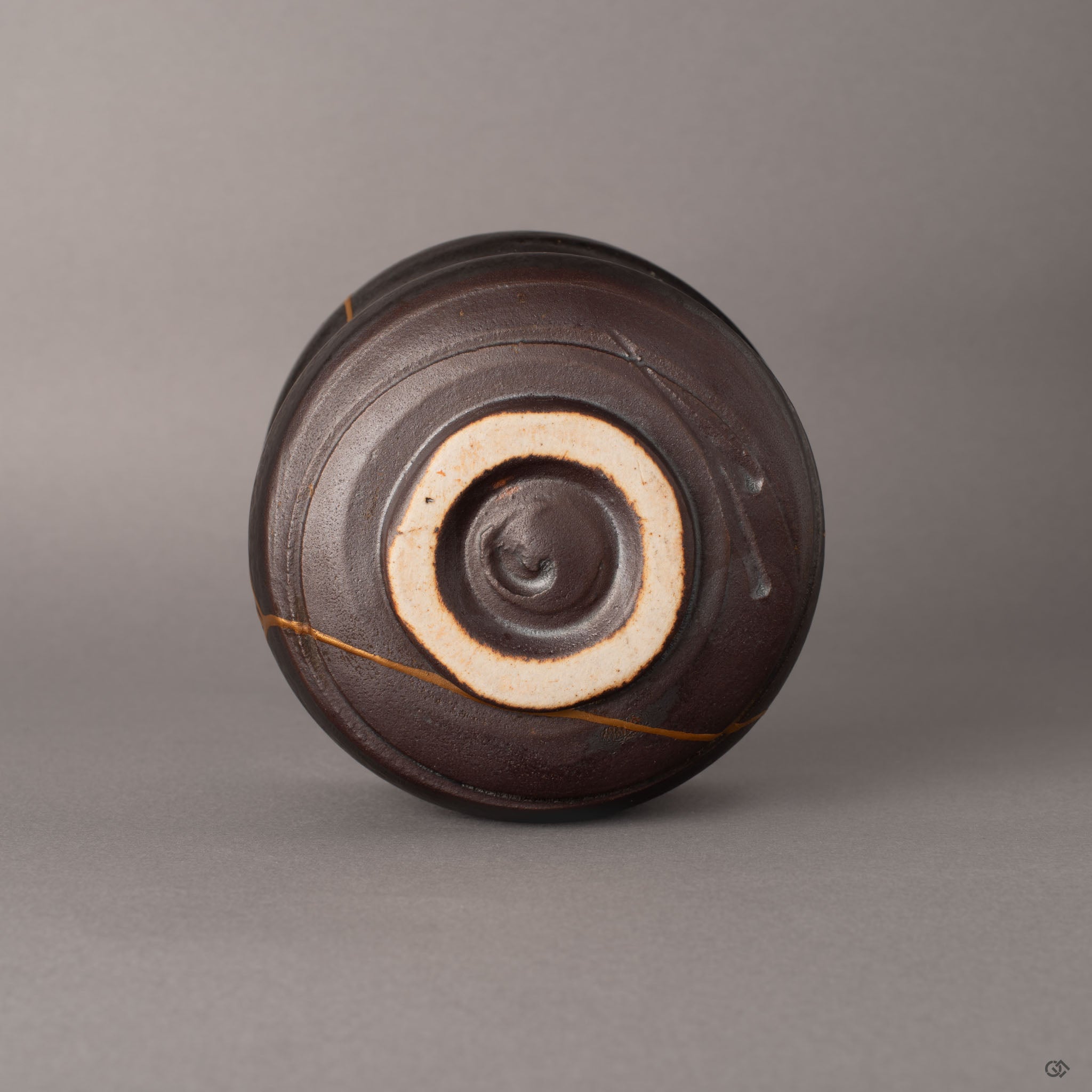 Bottom view of kintsugi Arita matcha bowl with unglazed foot ring and clay base, visible resilience in every restored edge.