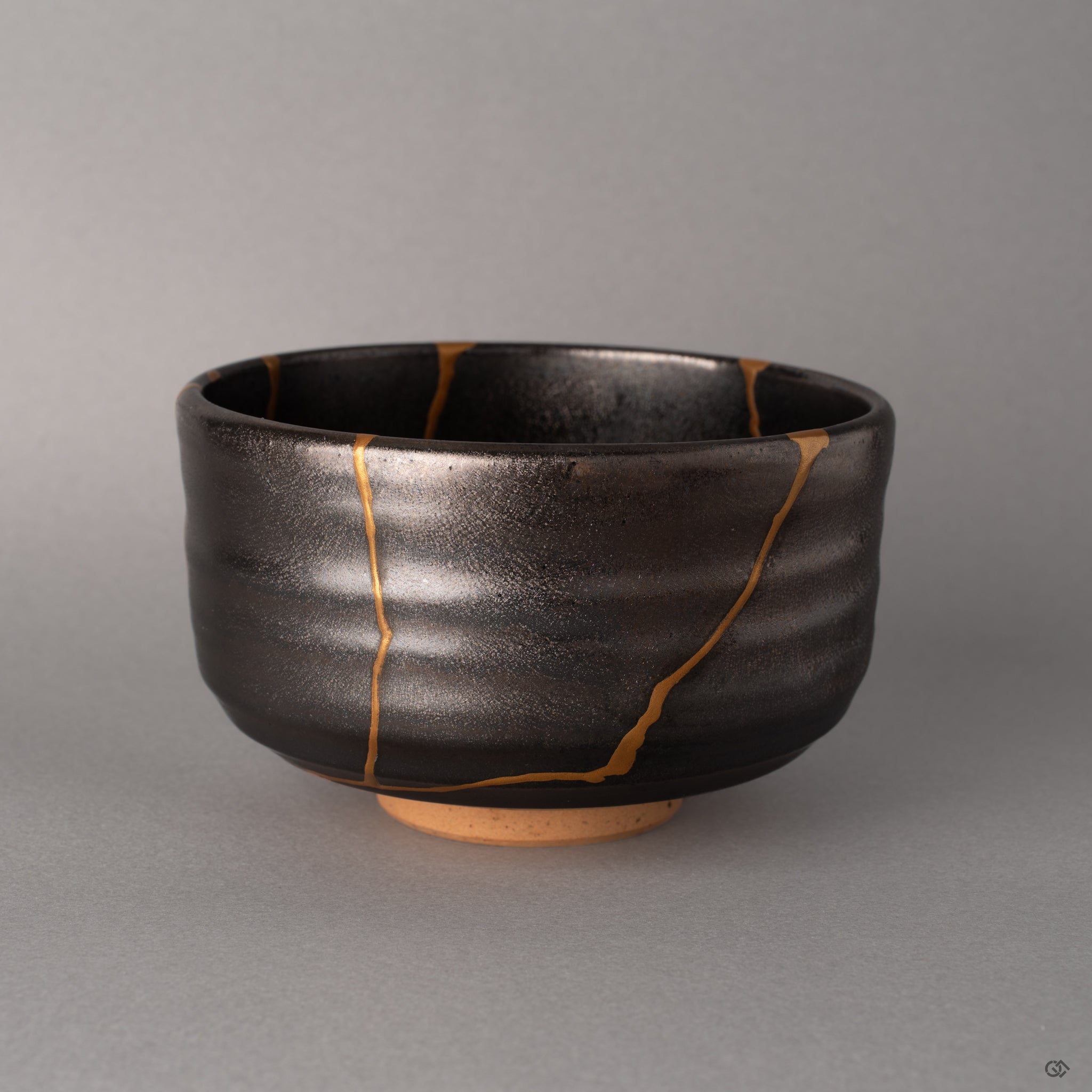 Profile of a dark gray Arita matcha bowl, its minimalist silhouette crossed by kintsugi gold, beauty in imperfection defined.