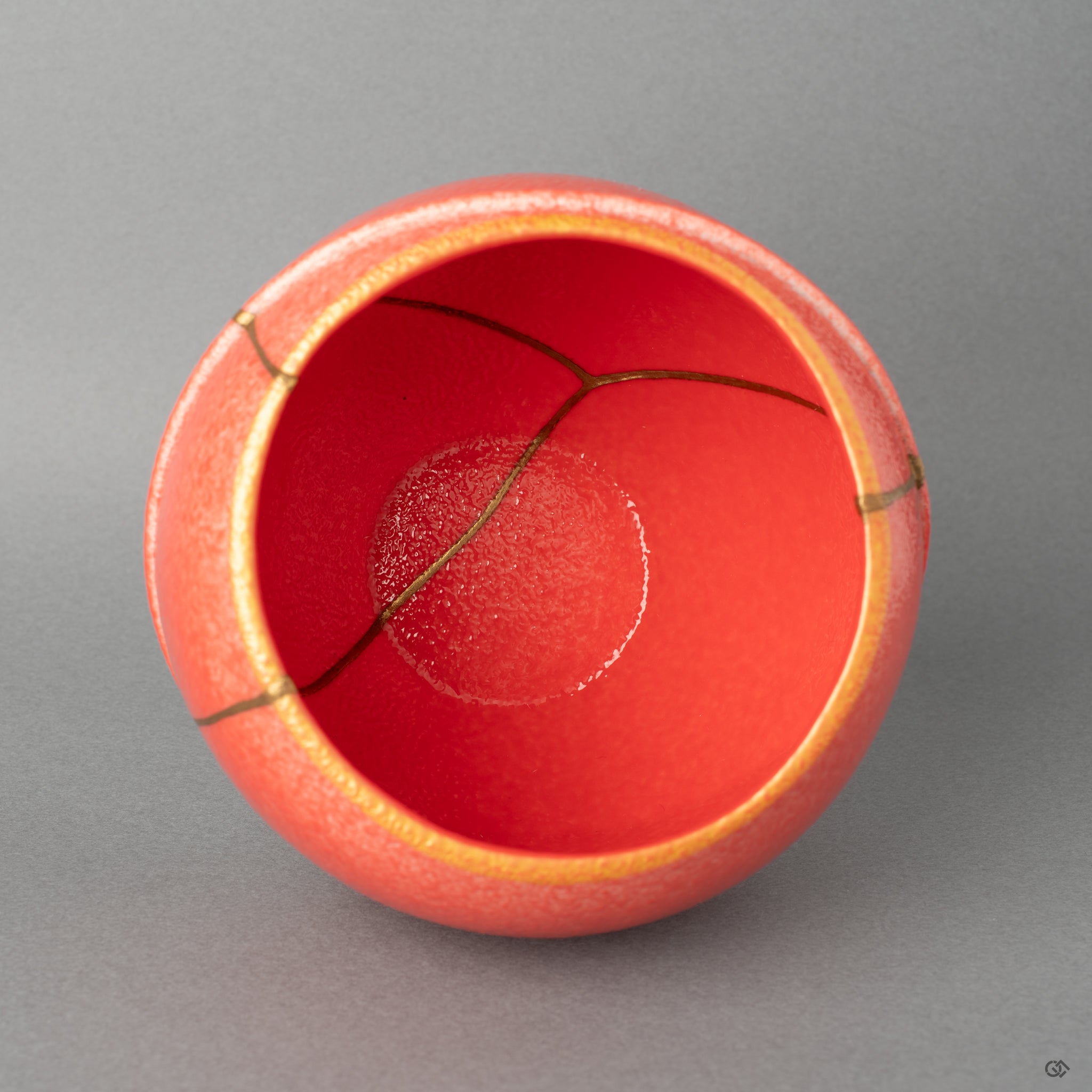 Top-down view reveals the wide rim and gold kintsugi joinery, a calm expression of beauty in imperfection held in red porcelain.
