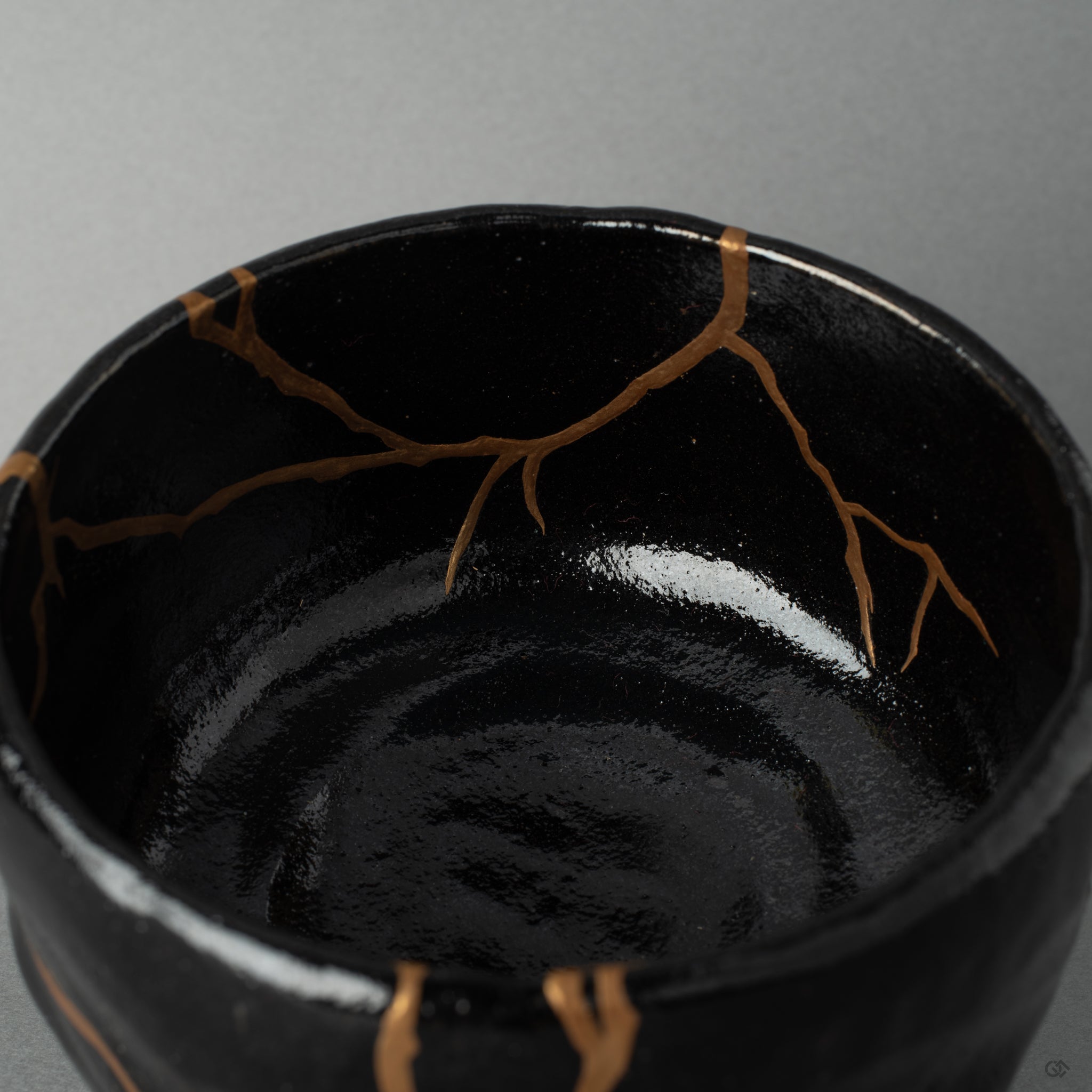 Interior close-up of gold kintsugi seams catching soft light, the mended surface a story in every seam.