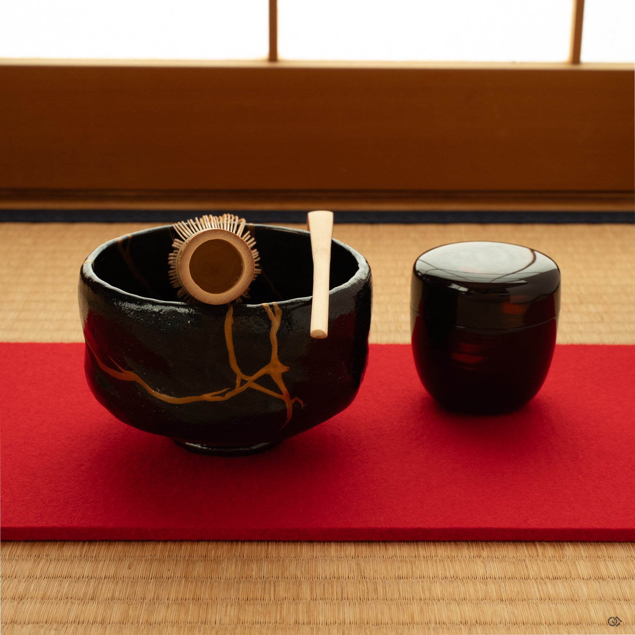 Kintsugi black matcha bowl on tatami in natural light, restored with gold and resting in a moment of contemplation.