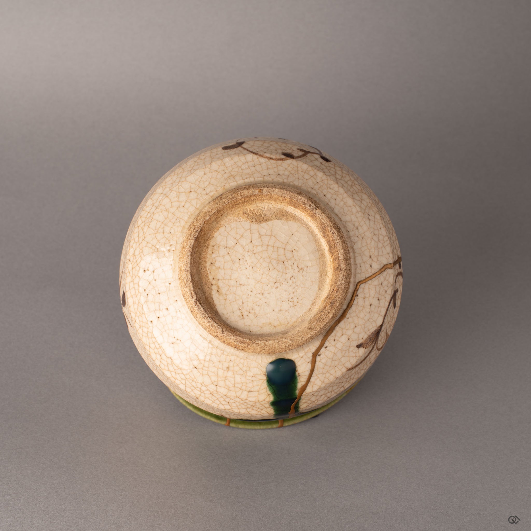 Bottom of a kintsugi Oribe matcha bowl showing the unglazed foot ring and earthenware base, crafted resilience from the kiln to the gold.
