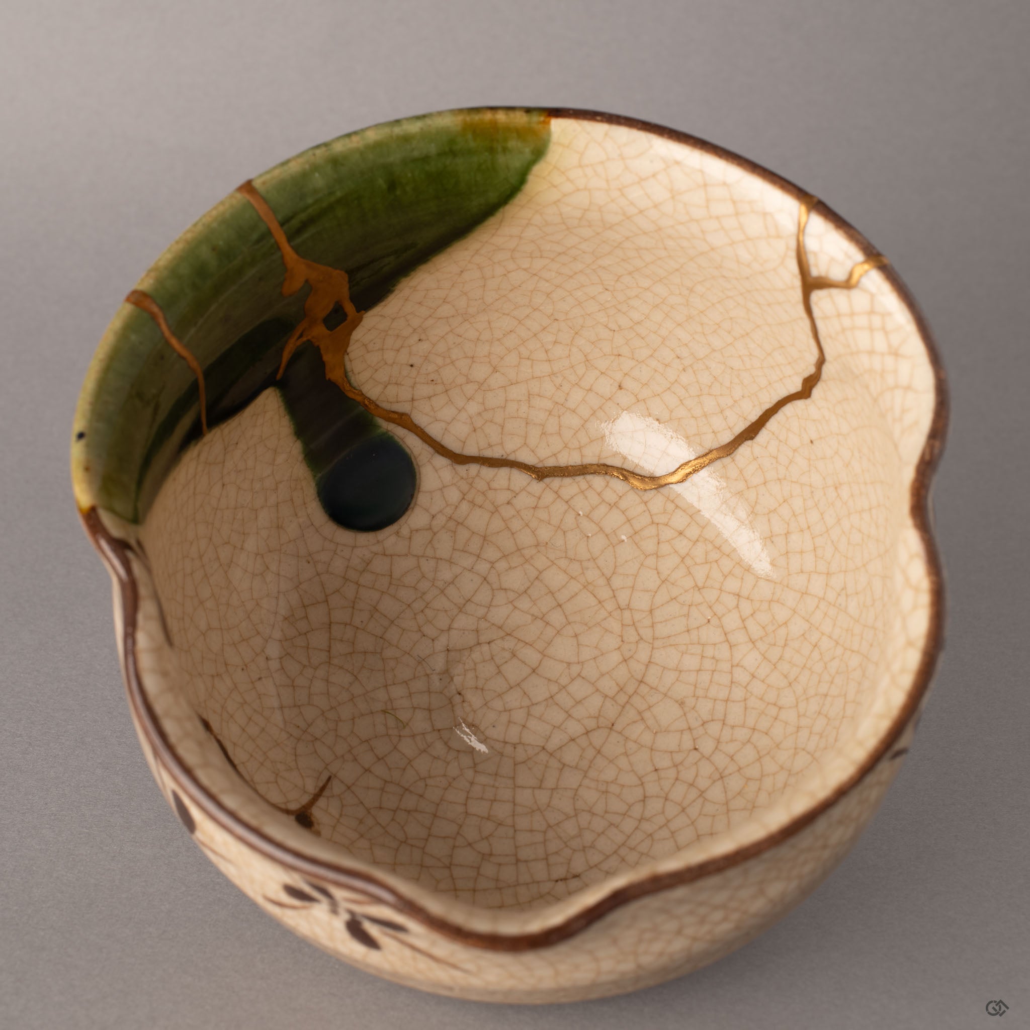 Interior close-up of a kintsugi Oribe matcha bowl showing gold lines converging inside the crackled glaze surface, tactile history in every seam.