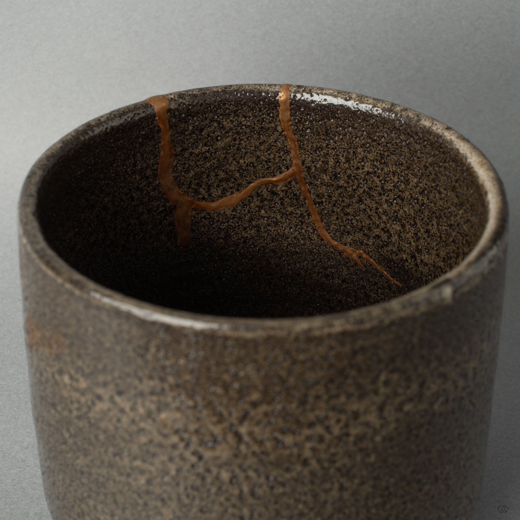 Interior close-up of gold kintsugi lines catching soft light, the mended surface holding a grace in flaws.