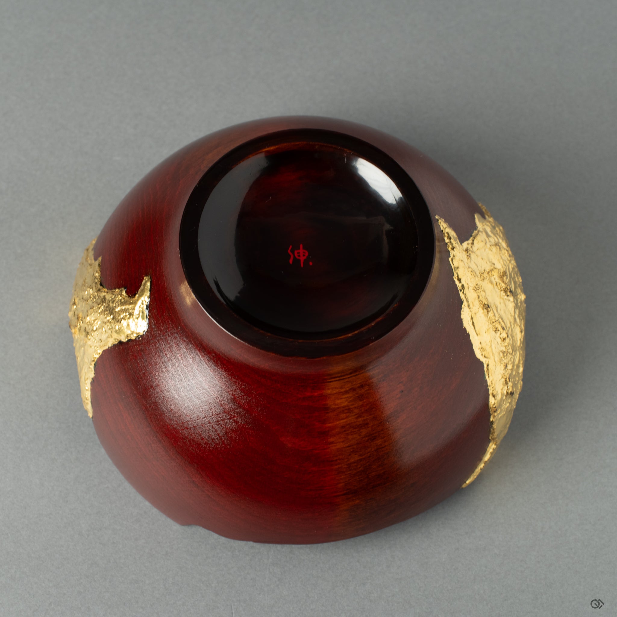Bottom view of a rock-like lacquerware piece with gold leaf on a lacquered wooden cup, crafted in the style of wabi-sabi. It exudes wabi-sabi elegance and Japanese artistry.